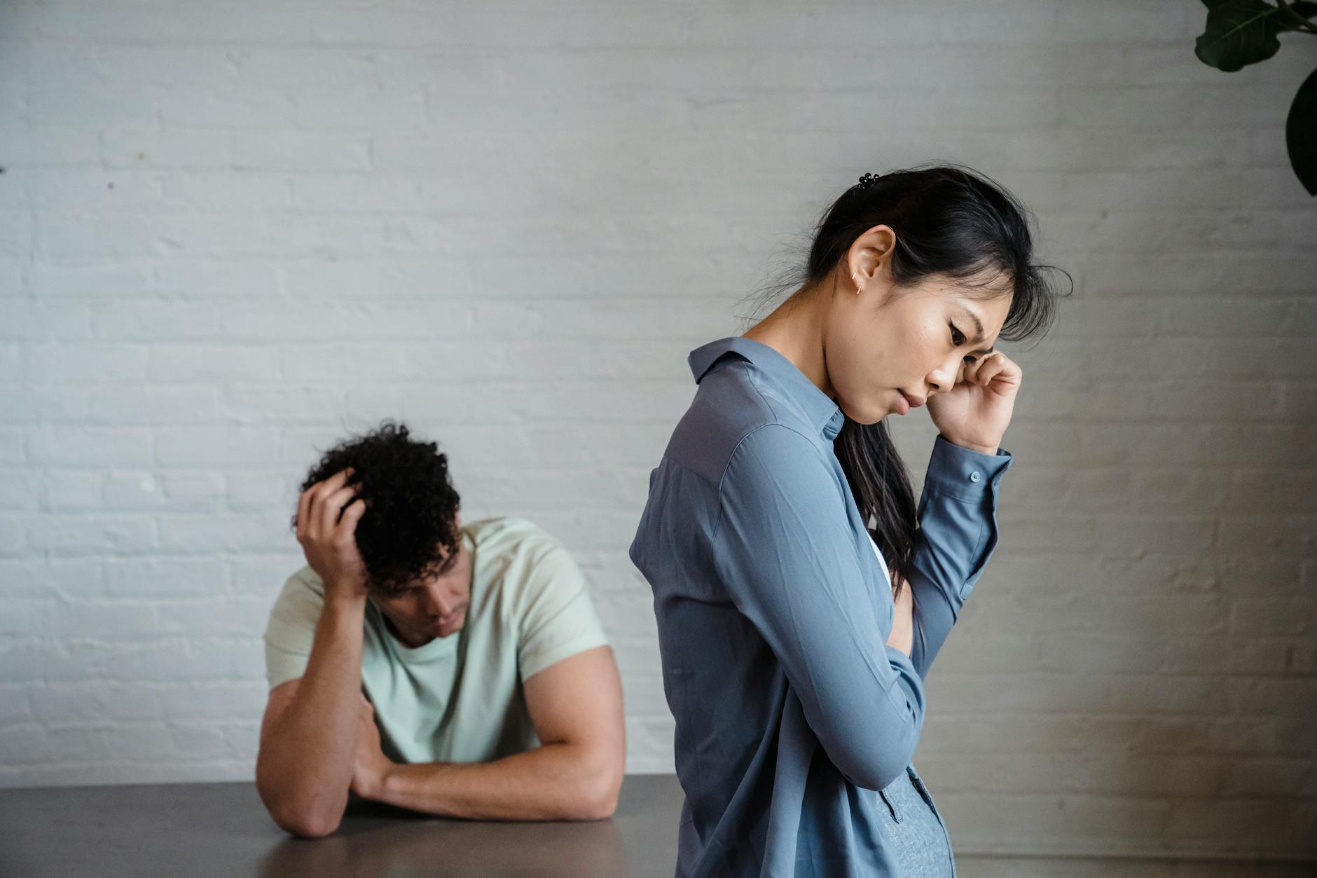An Asian woman and man feeling misunderstood and frustrated in a relationship indoors. - conflict resolution definition