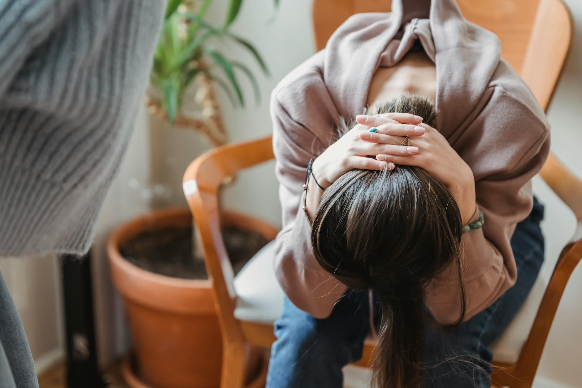 A woman sitting with her head in her hands, expressing distress inside a room. - conflict resolution definition