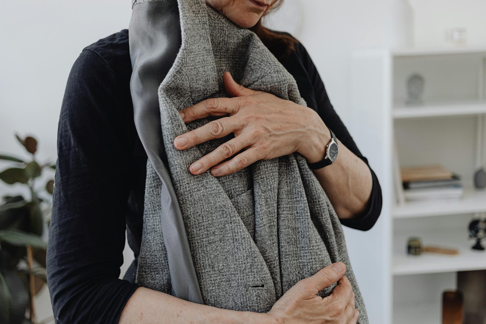 A woman embracing a blazer, symbolizing grief and loss, in a calming home setting. - coping with grief in winter