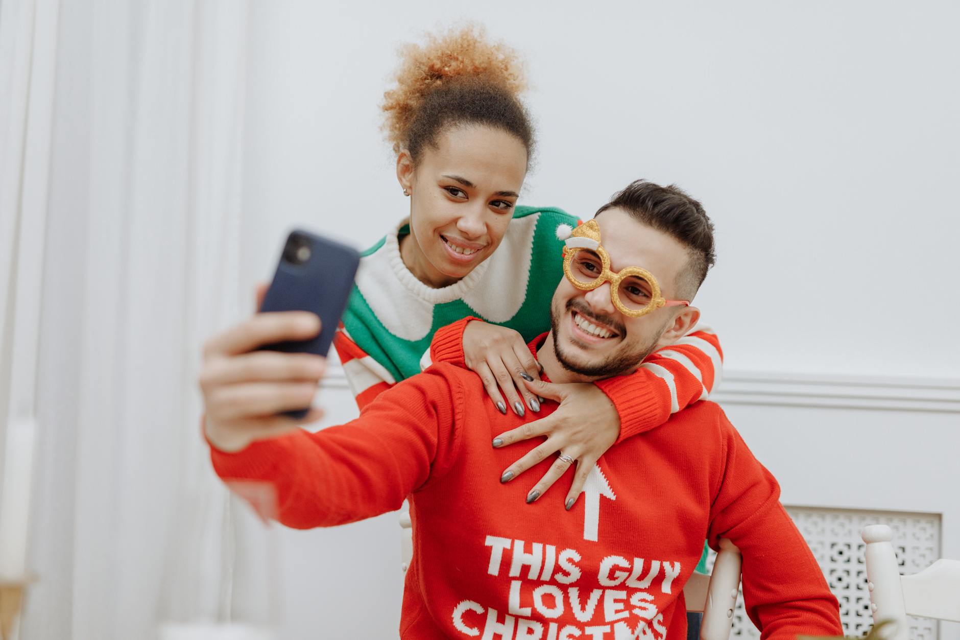 Interracial couple capturing a joyful moment in Christmas sweaters, embracing the holiday spirit. - couples therapy holiday season