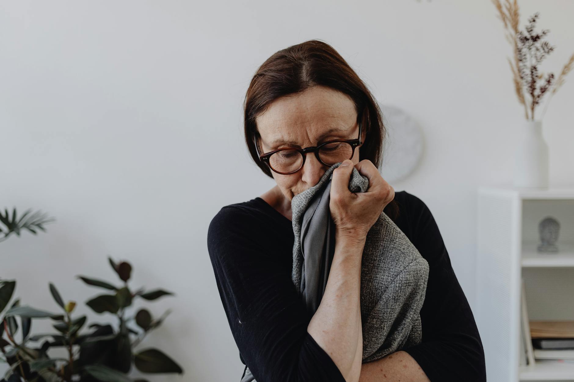A middle-aged woman grieves while holding a cloth in an indoor setting. - depression coping mechanisms