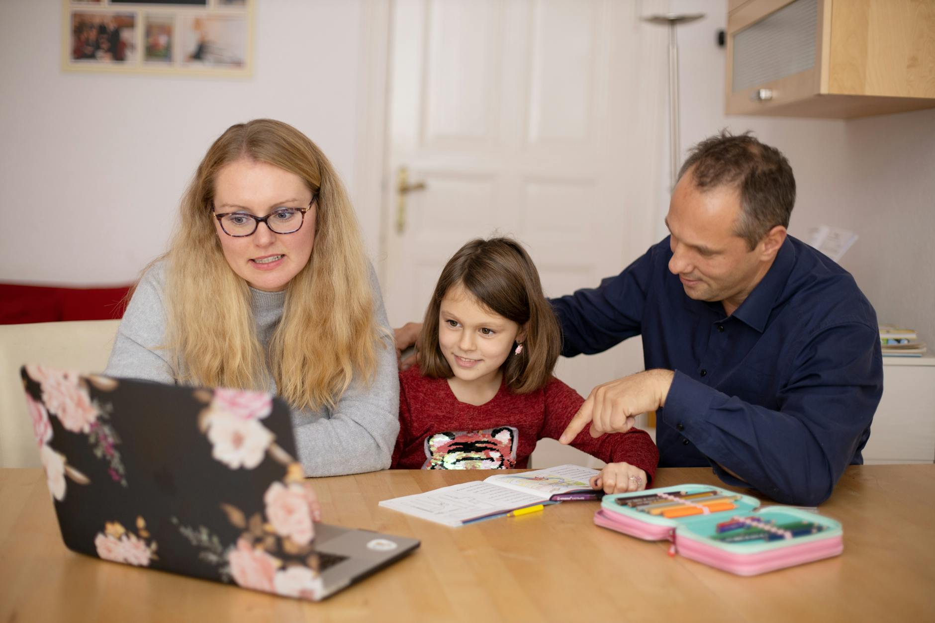 A family is engaged in homeschooling, using technology to learn together in a cozy home setting. - february school break parenting