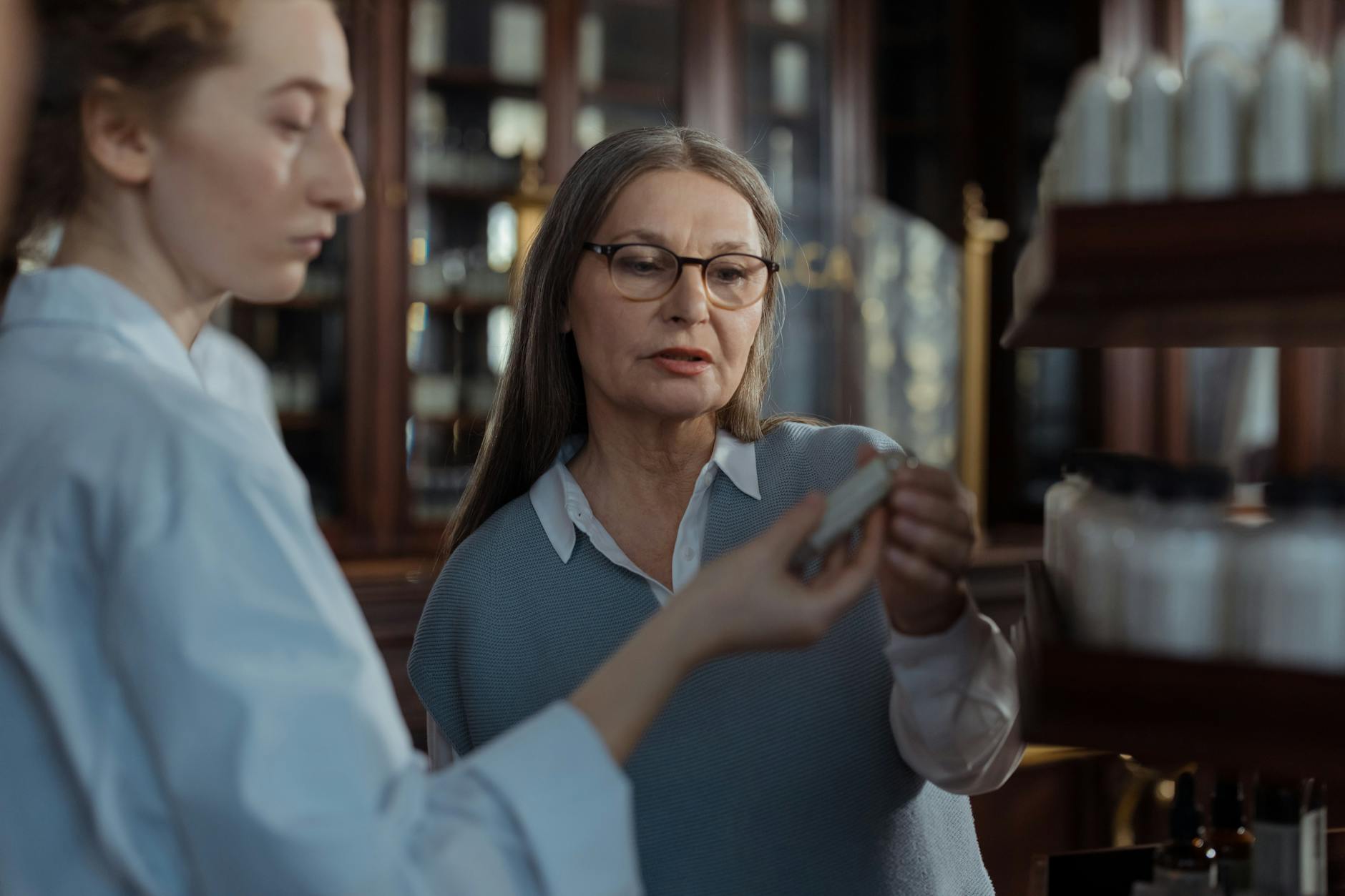 An elderly woman discussing medication options with a pharmacist at a pharmacy counter. - funny advice for newlyweds