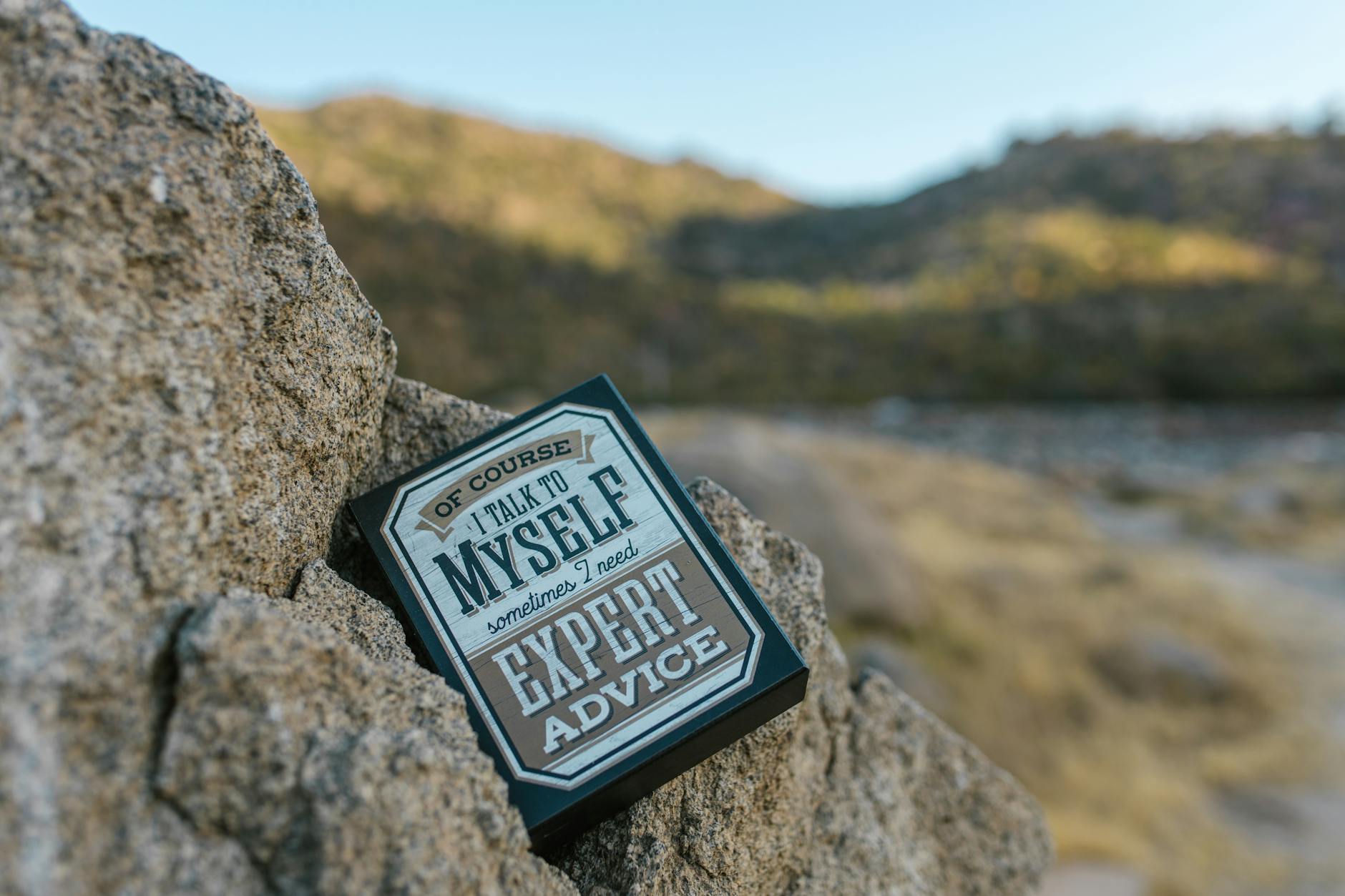 Close-up of a humorous motivational sign placed on rocks in an outdoor setting. - funny marriage advice