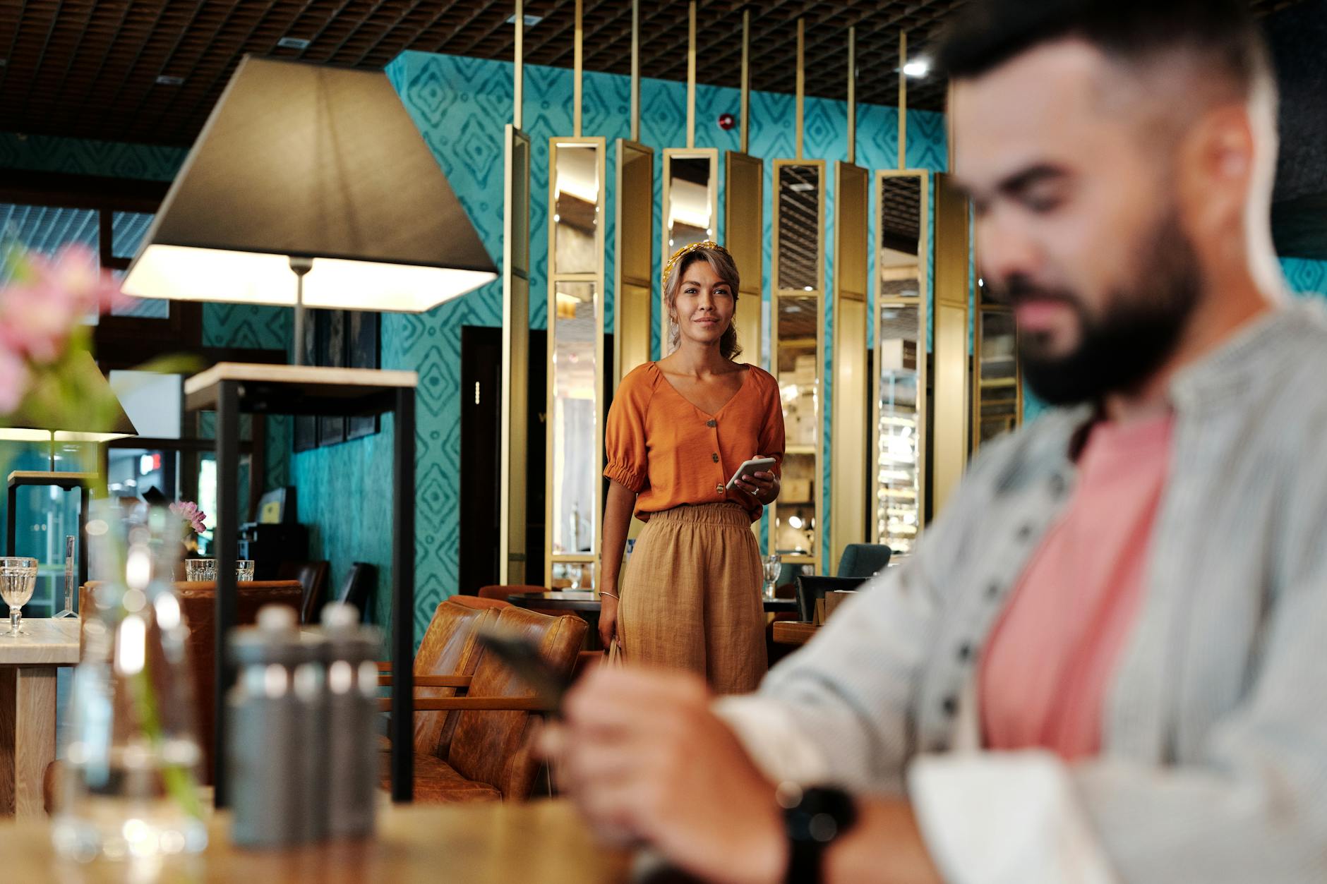 A man and woman at a modern restaurant setting, with warm interior decor. - good first date questions