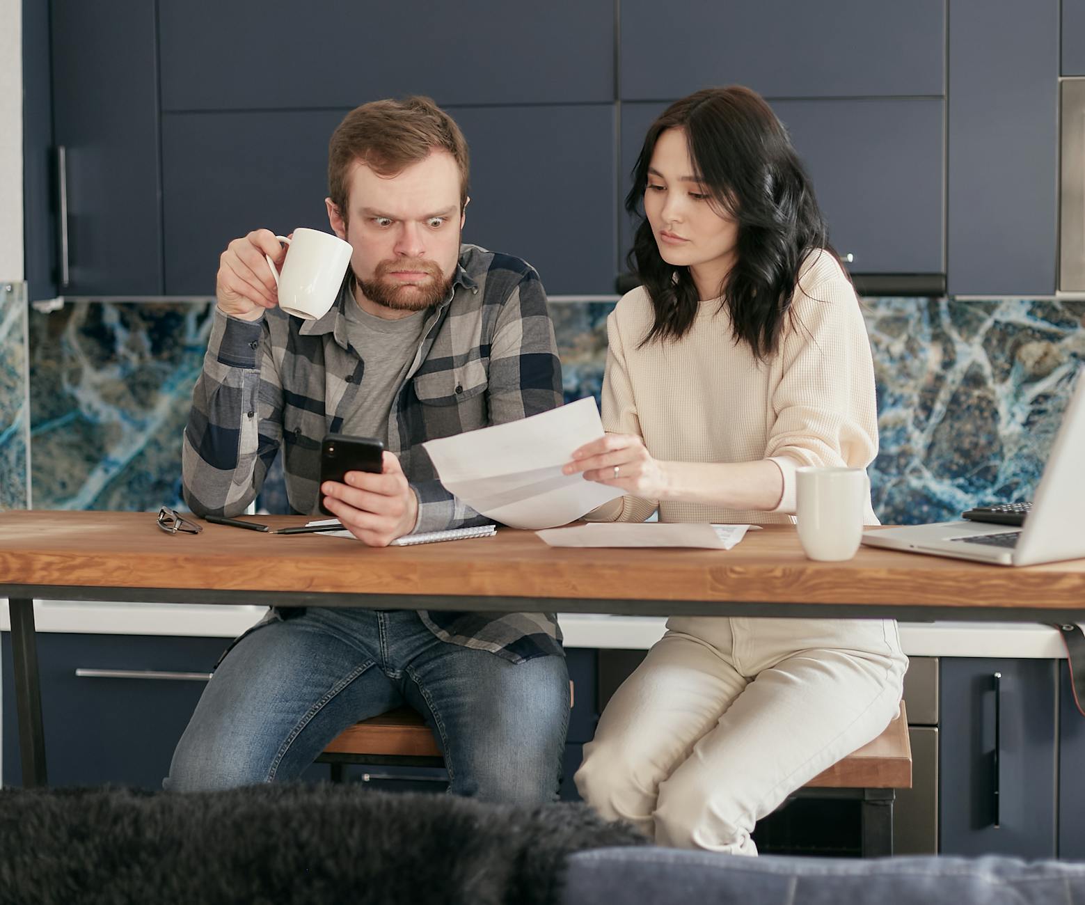 A couple looks concerned while reviewing financial documents together at home. - holiday financial stress relationships