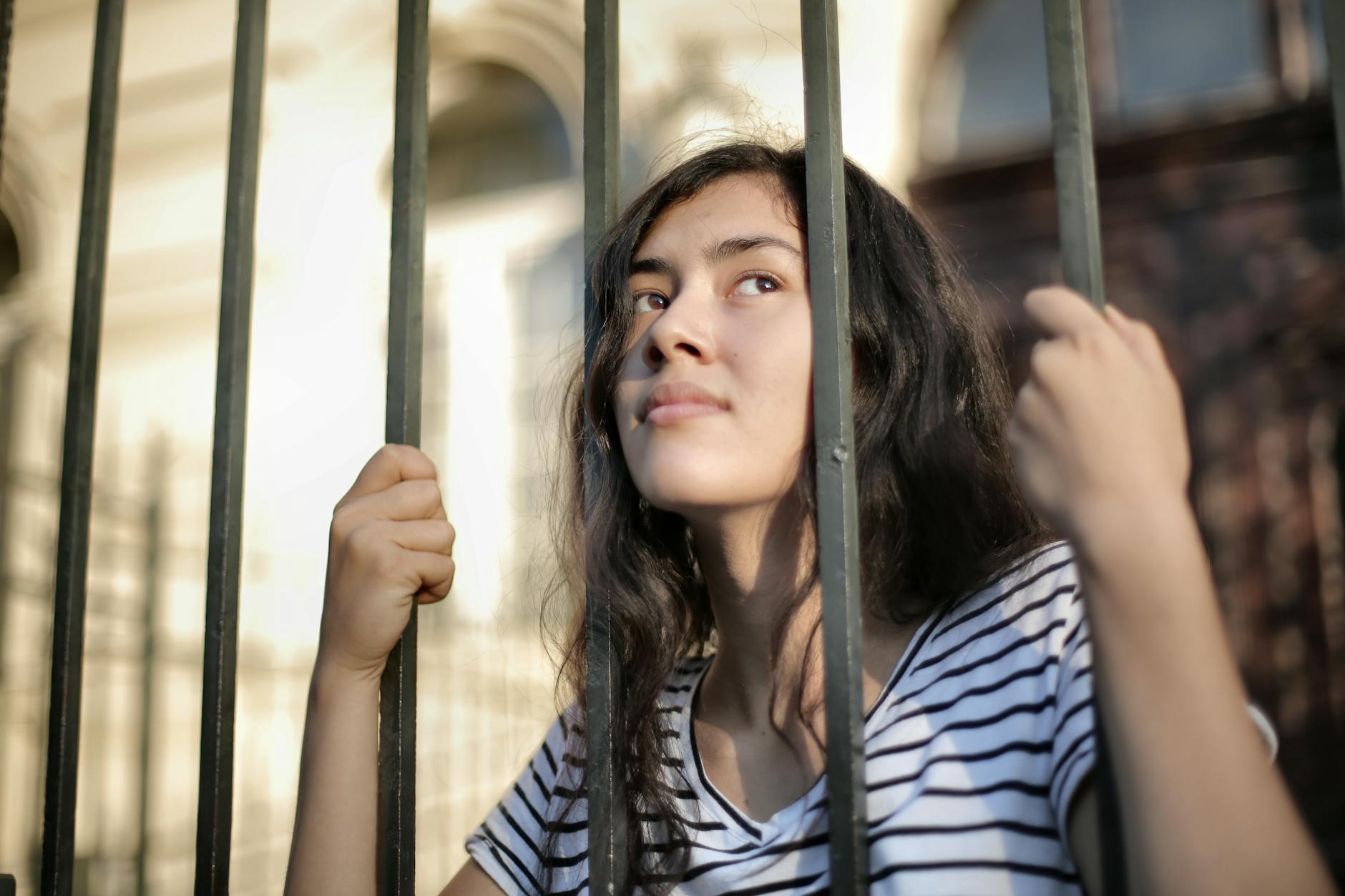 A teenage girl looks thoughtfully through bars, symbolizing hope and freedom. - introvert dating advice