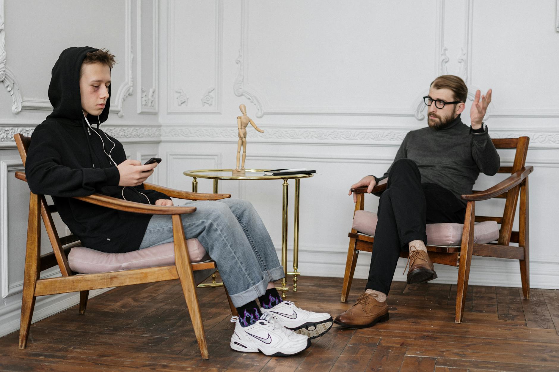 Teenage boy in hoodie during a therapy session with a male therapist. - light therapy for sad
