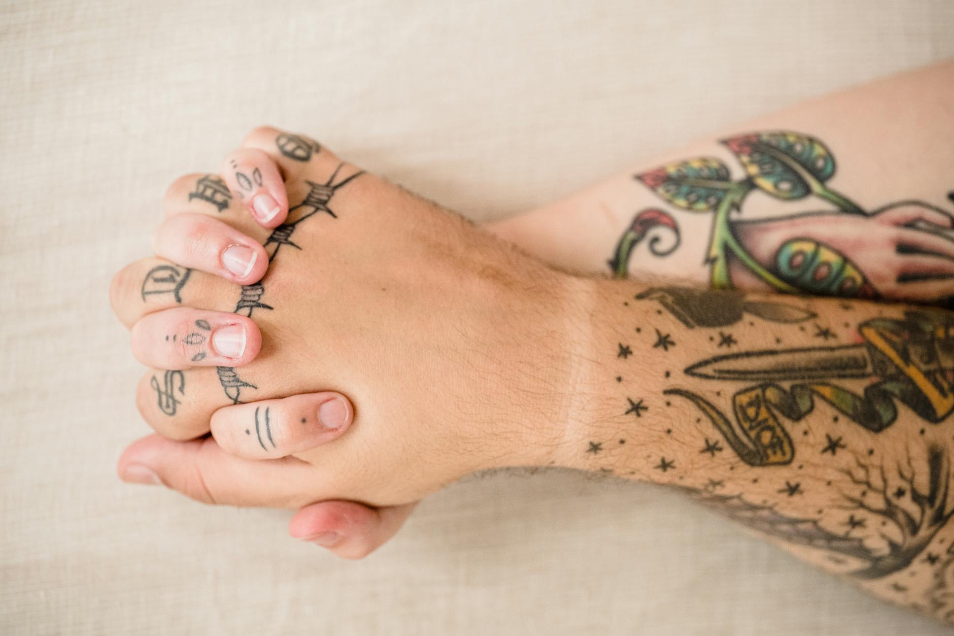 Two tattooed hands clasped together, symbolizing love and connection. - love bombing meaning