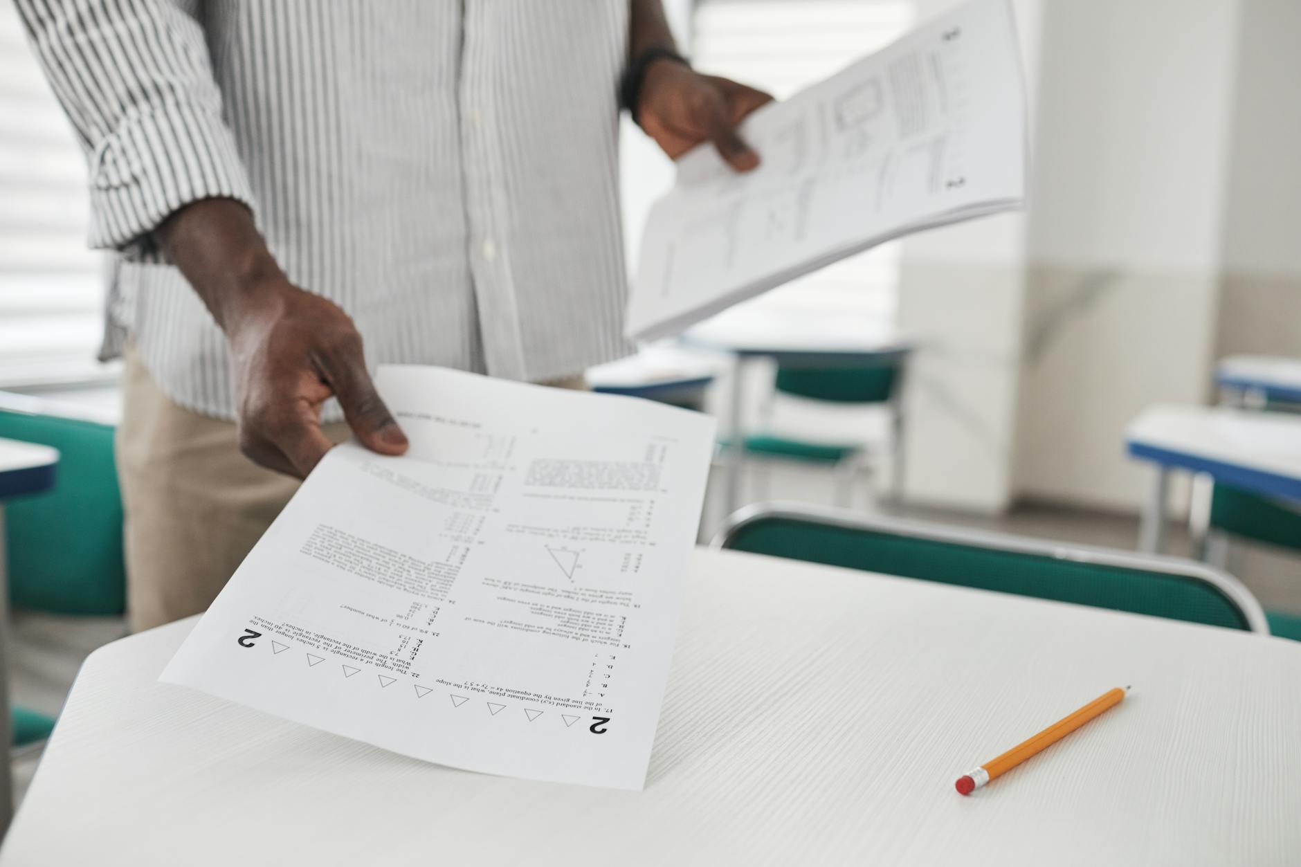 Close-up of a person arranging examination papers on a desk in a classroom. - love language quiz