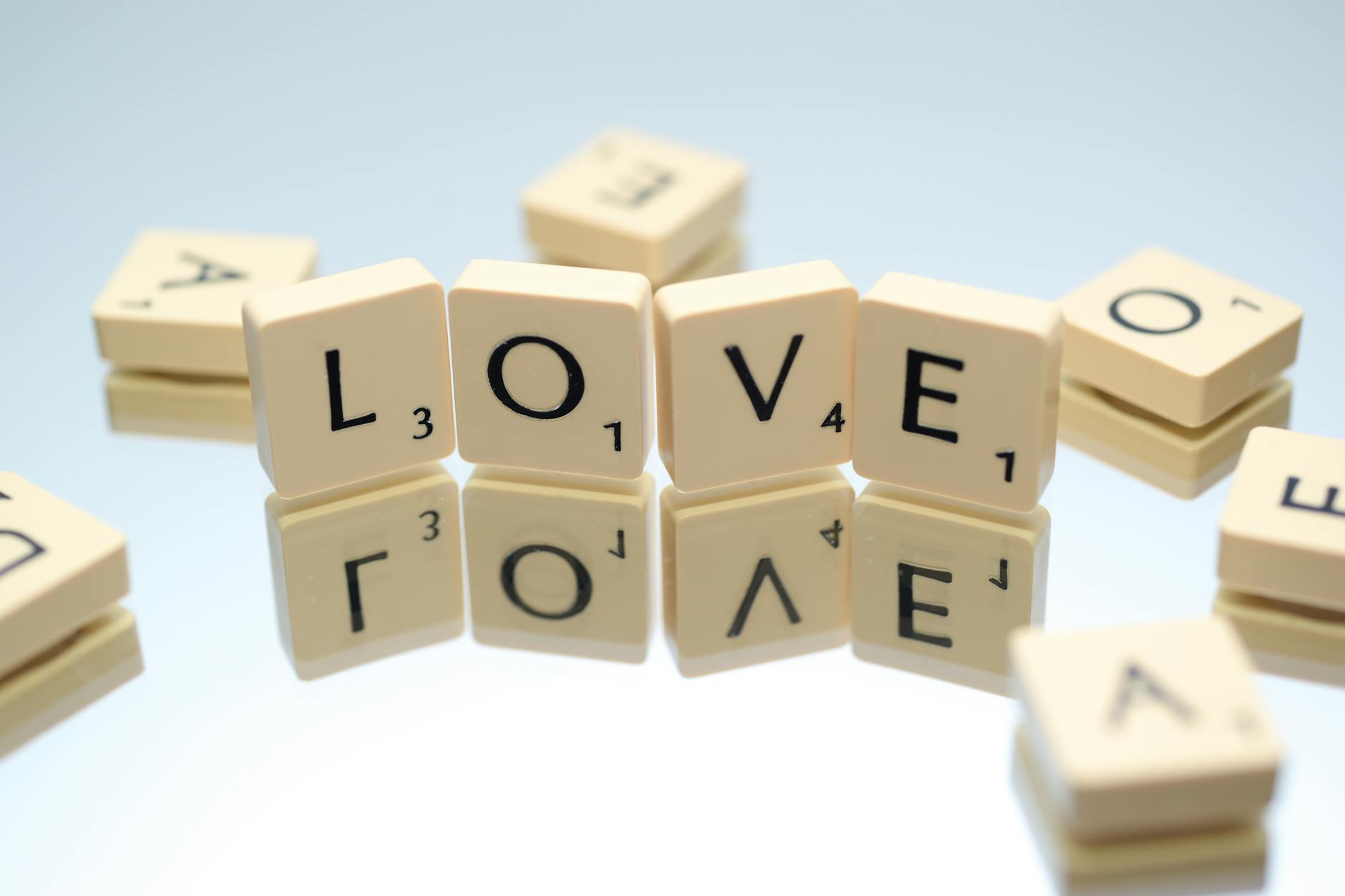 Scrabble tiles spelling LOVE on reflective surface, creating conceptual design. - love language quiz