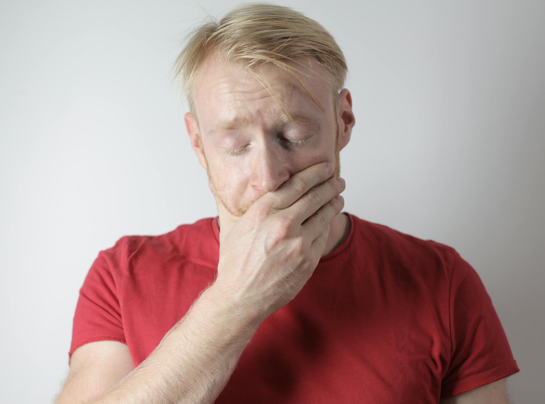 Mature man in red t shirt being in shock after getting news standing with closed eyes near gray wall in room - manage kids winter frustration