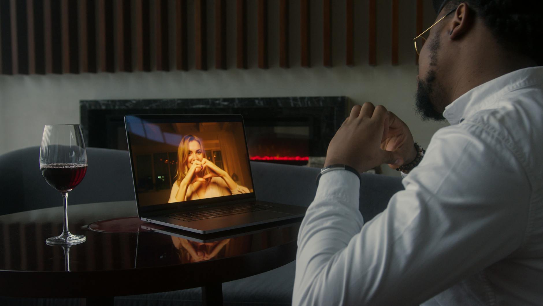Man having a video call date with wine, enjoying a cozy and intimate atmosphere. - online dating tips men