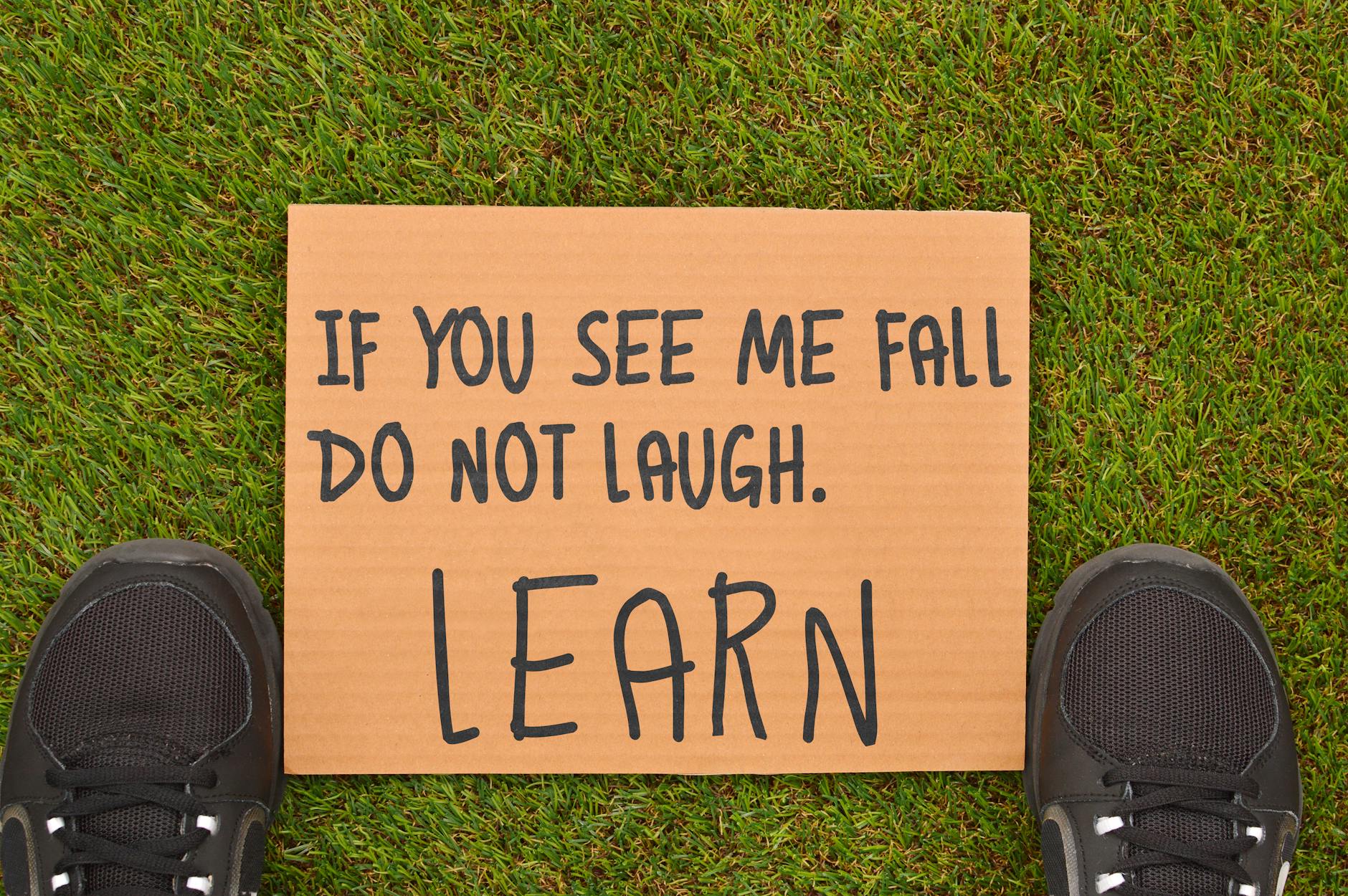 Cardboard sign with motivational message beside sneakers on green grass. - overcoming winter loneliness