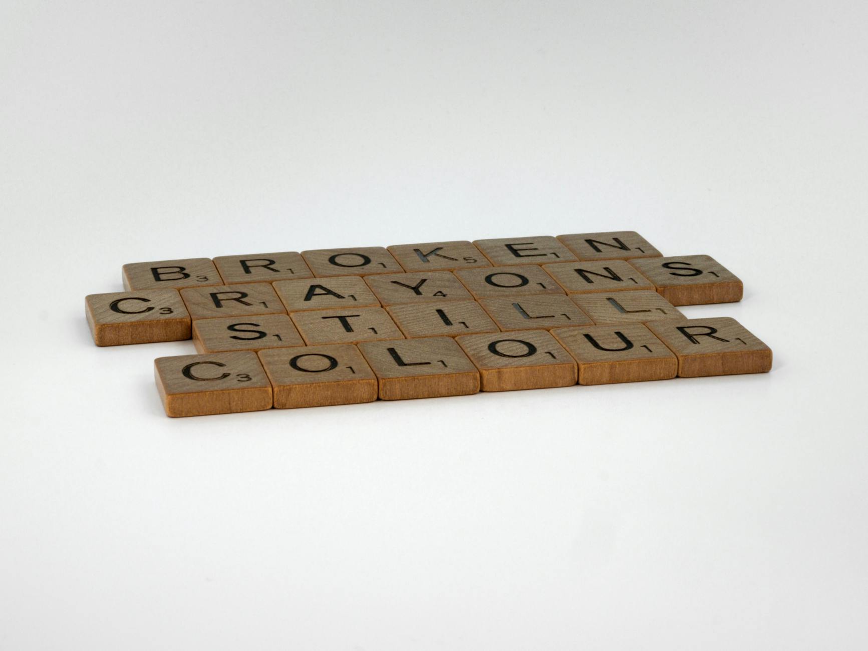 Scrabble tiles spelling 'Broken Crayons Still Colour' on white background, promoting creativity. - overcoming winter perfectionism