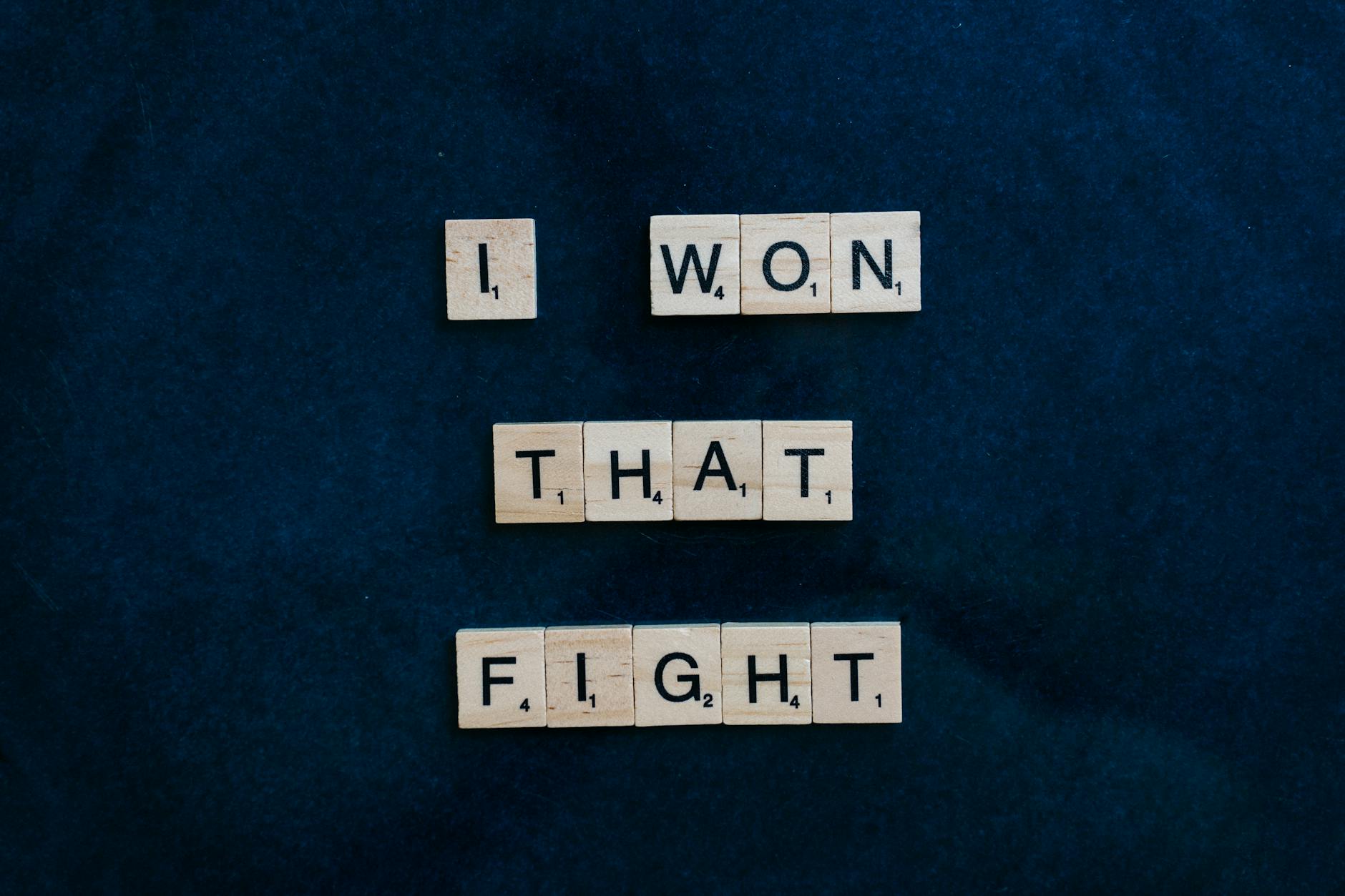 Wooden Scrabble tiles on dark background spelling 'I won that fight.' - overcoming winter perfectionism