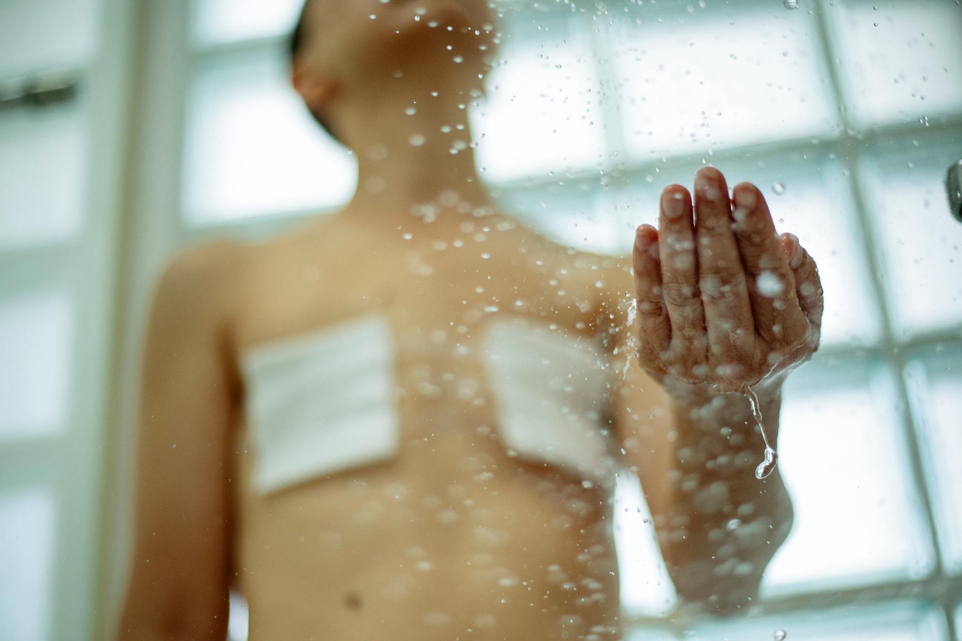 A person with bandages and scars in the shower, illustrating self-care and recovery. - peter levine trauma healing