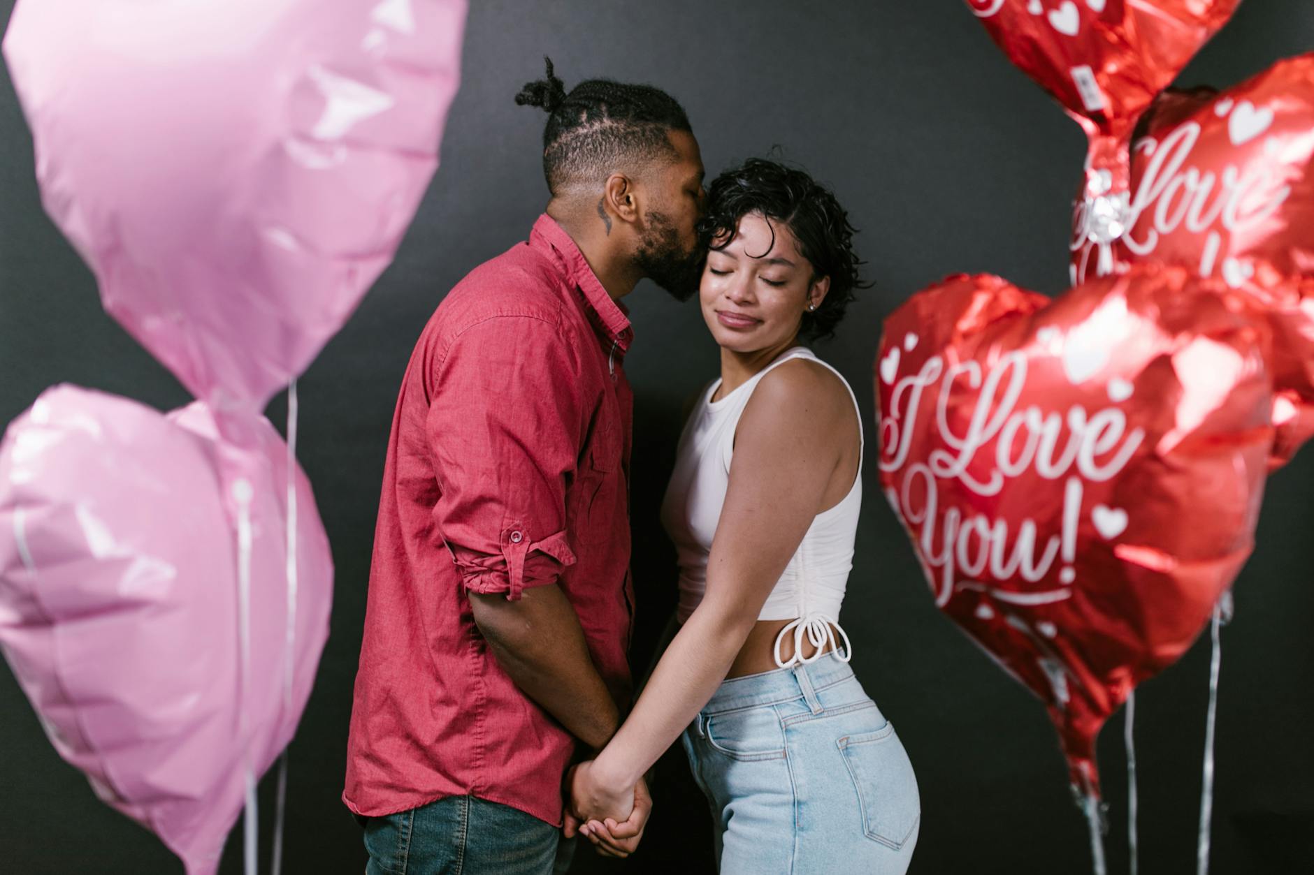 Romantic couple holding hands surrounded by heart-shaped balloons, celebrating love. - post valentine's relationship expectations