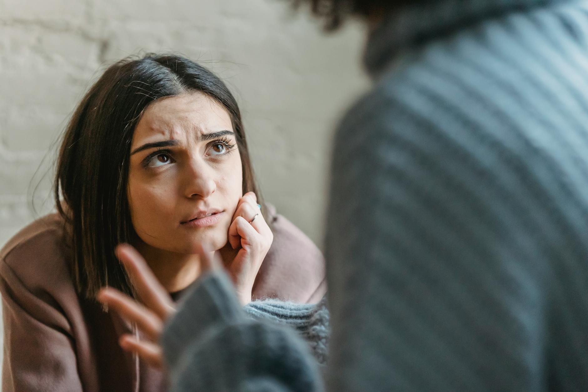 Woman listening thoughtfully during a serious conversation indoors. - how to resolve conflict