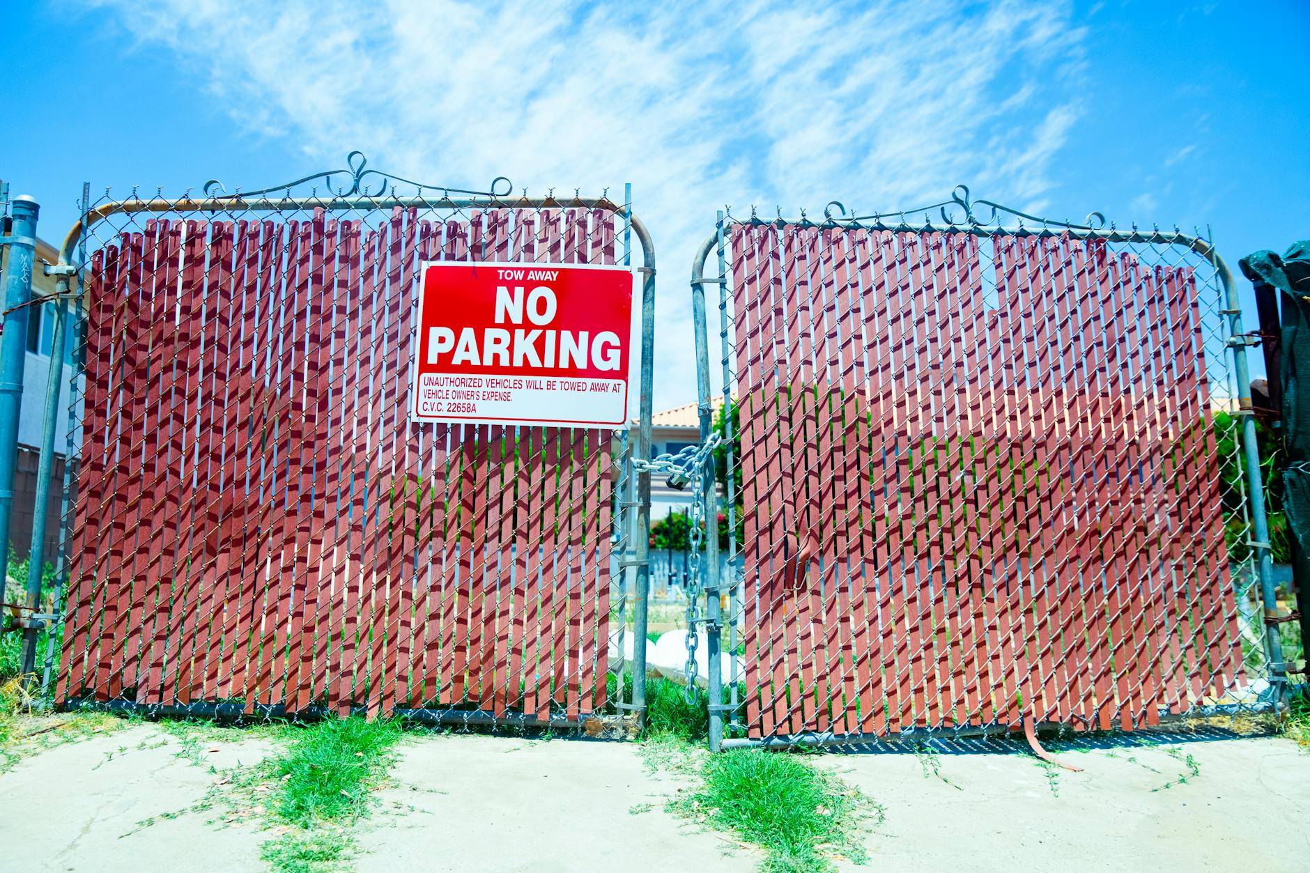 Red 'No Parking' sign on a metal gate with a vibrant blue sky background. - setting boundaries holidays