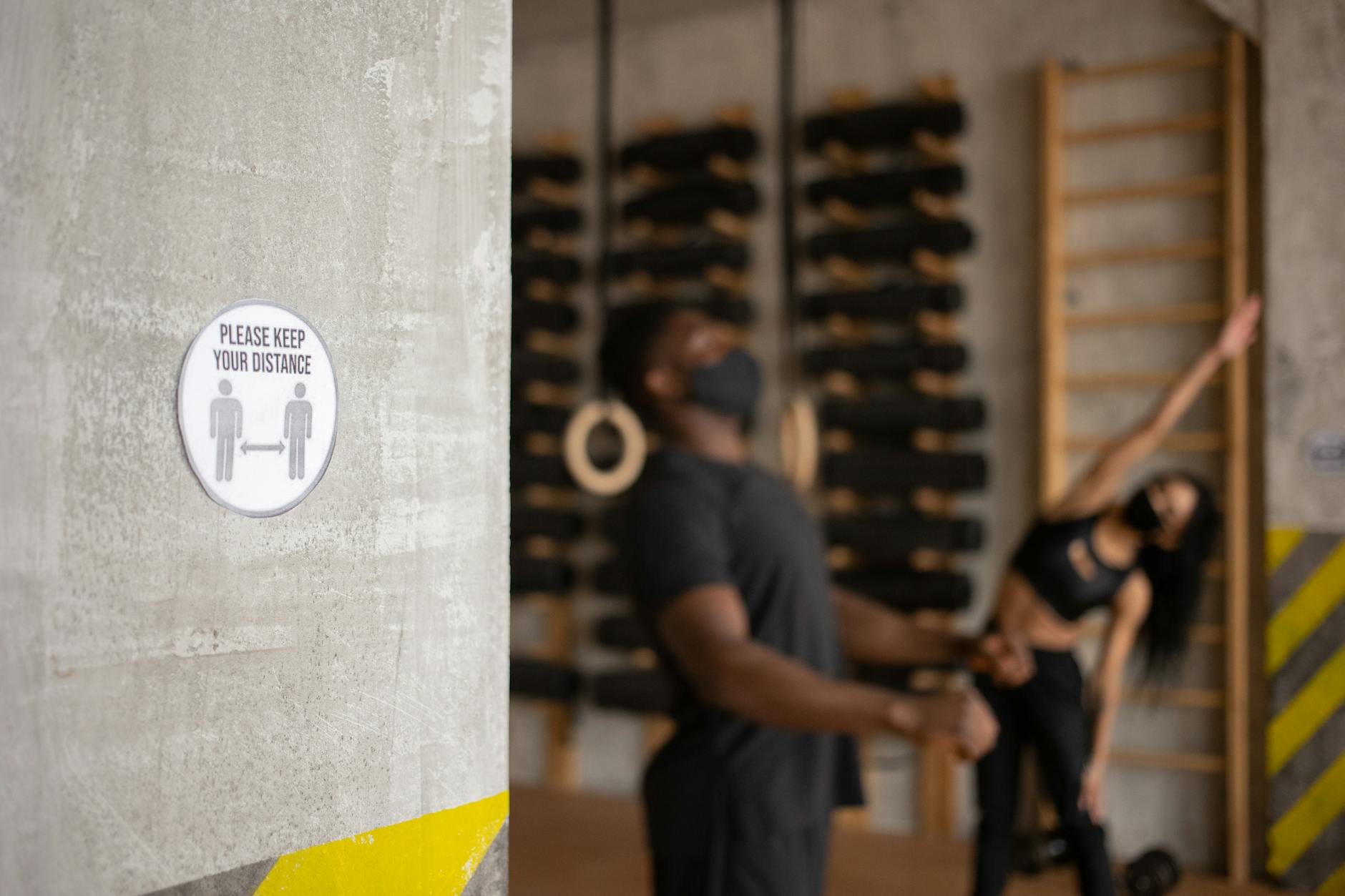Two people exercising indoors with a social distancing sign prominently displayed. - signs of narcissist partner