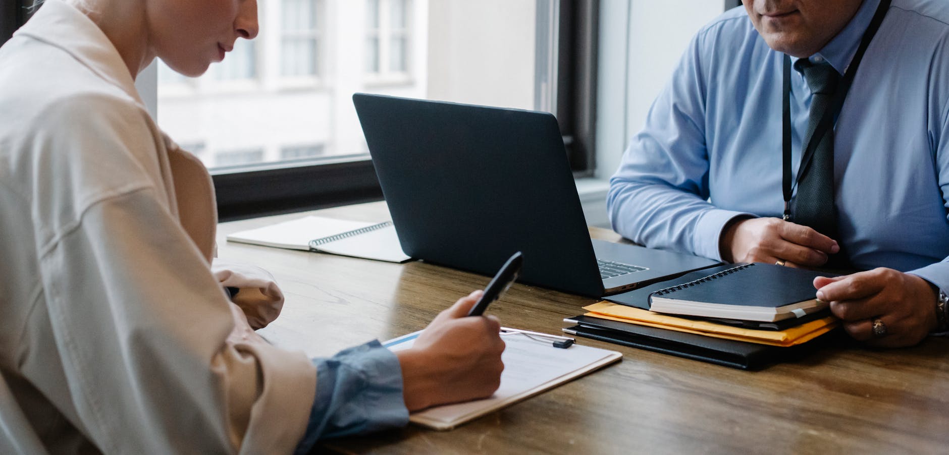 Two professionals engaged in a business meeting, discussing documents with a laptop at the office. - signs of narcissist partner