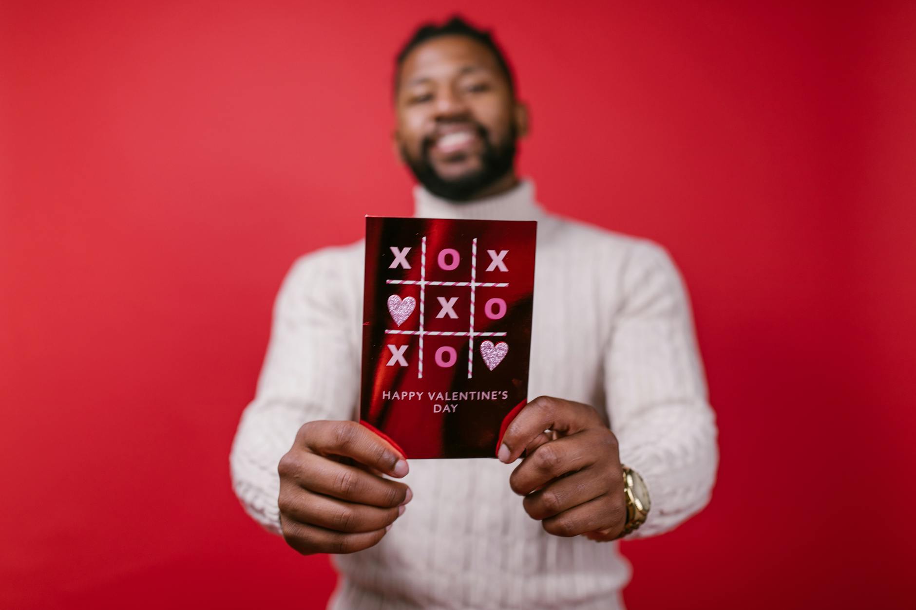 A joyful man presenting a Valentine's Day card with a red background, symbolizing love and celebration. - single parent valentine's day
