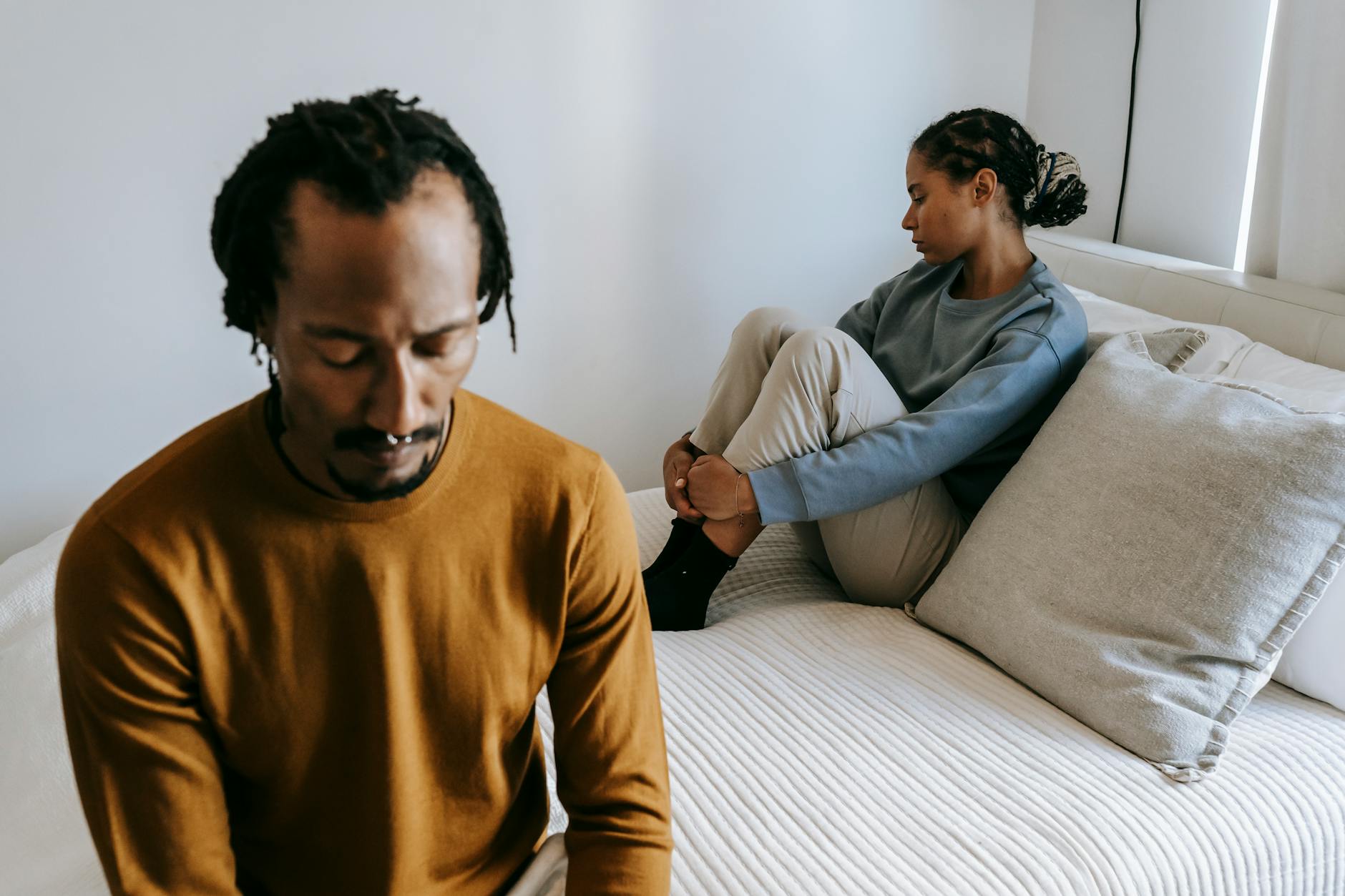 Young black couple in casual outfit spending time on bed with sad face in daytime at home - therapy for winter apathy