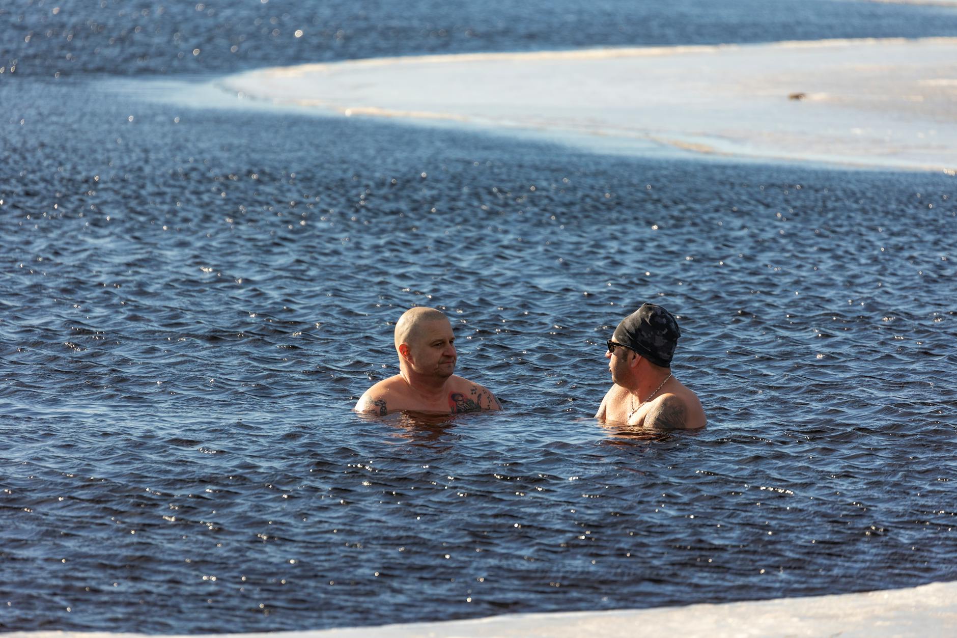 Two men enjoying winter swimming in icy waters, showcasing extreme cold exposure. - therapy for winter slump