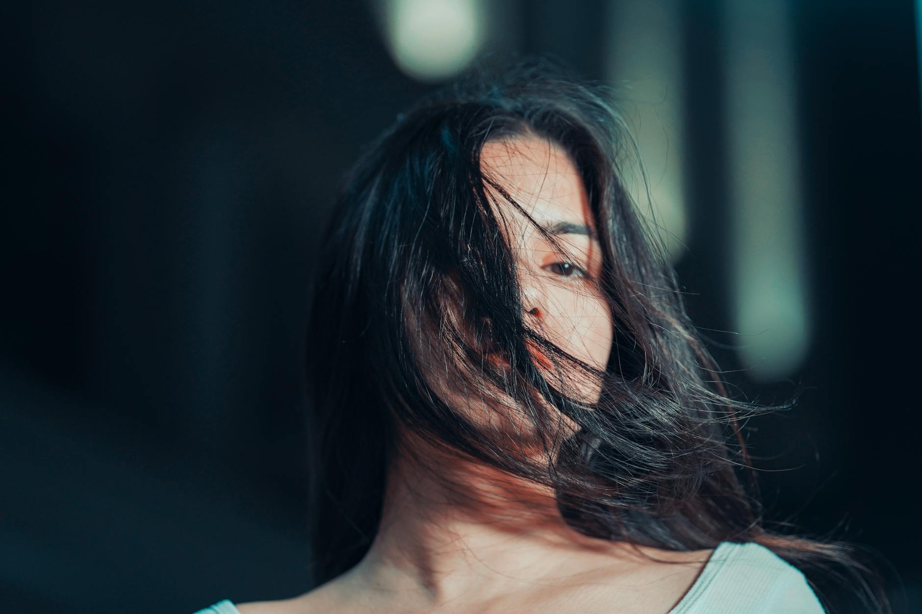 Close-up portrait of a woman with dramatic lighting and hair blowing across her face. - winter love languages ideas