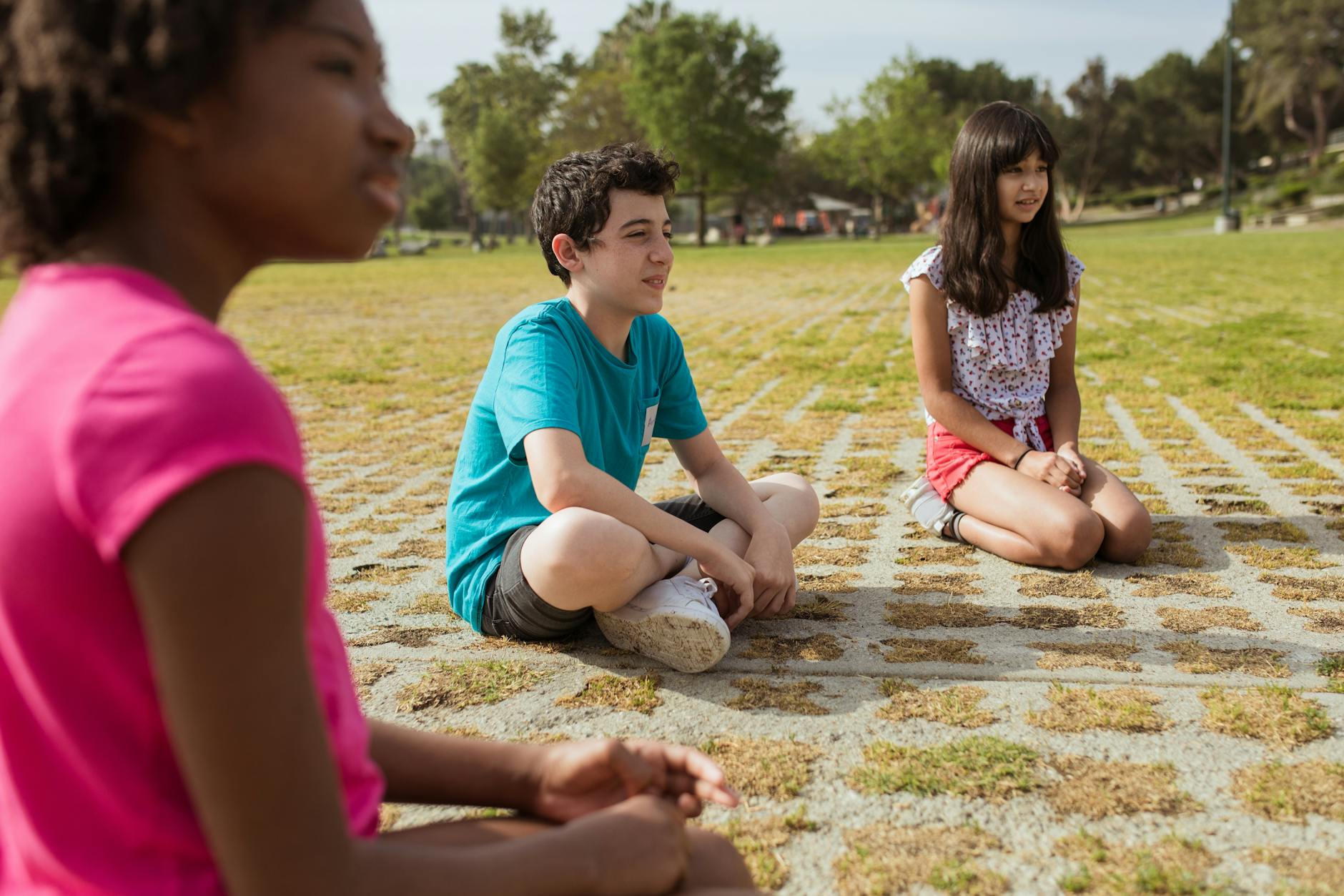 Kids sitting together in a green park during summer camp for team building and fun. - winter social skills for kids