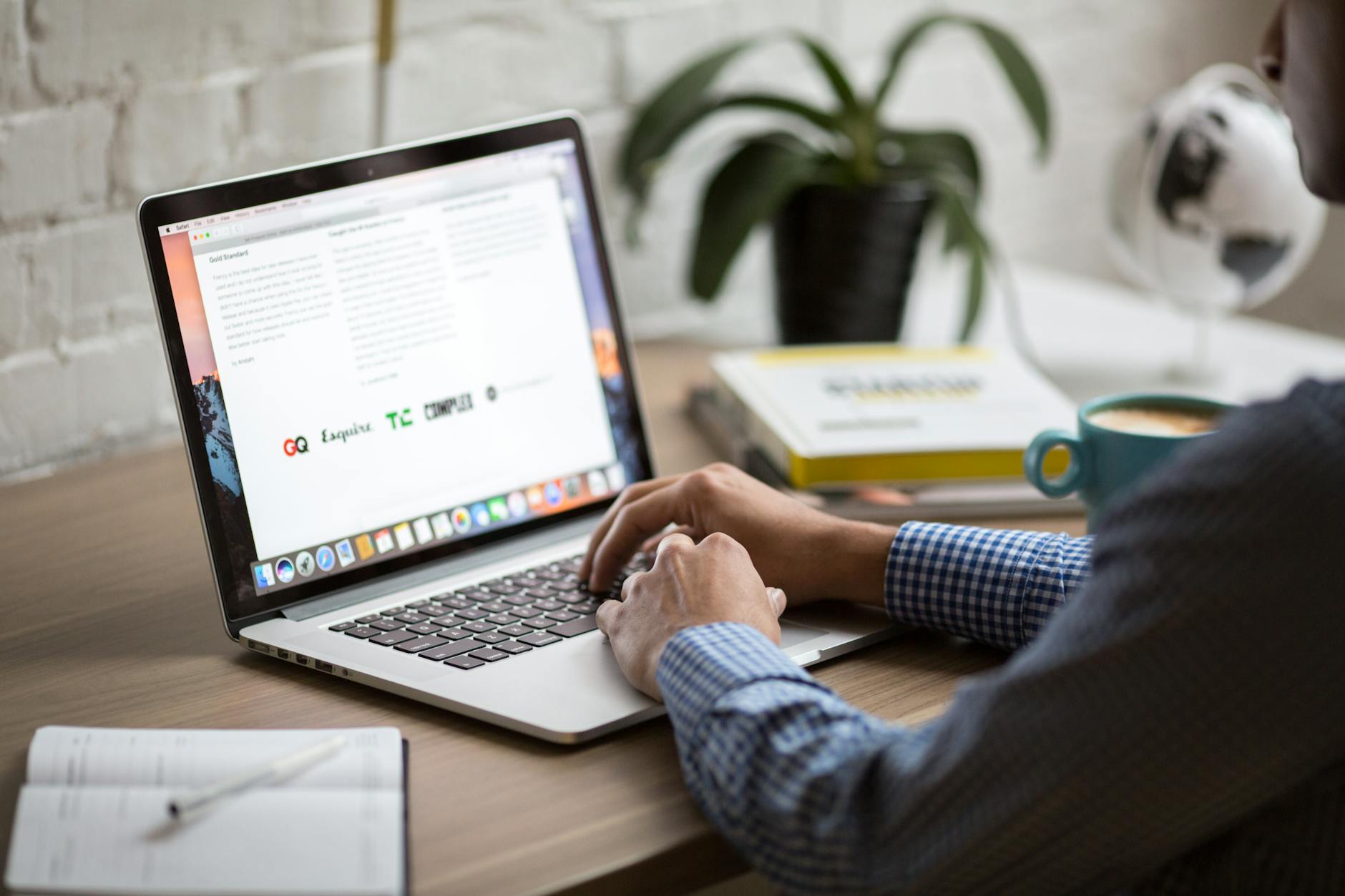 A man working on a laptop at a desk with coffee, showcasing remote work in a modern office setting. - write apology email