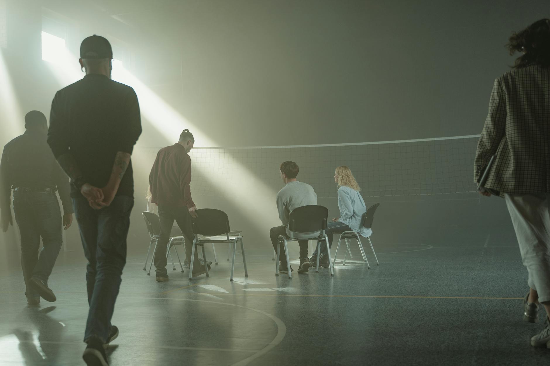 A group therapy session with diverse adults in a dimly lit gymnasium, highlighting mental health support. - acceptance and commitment therapy spring