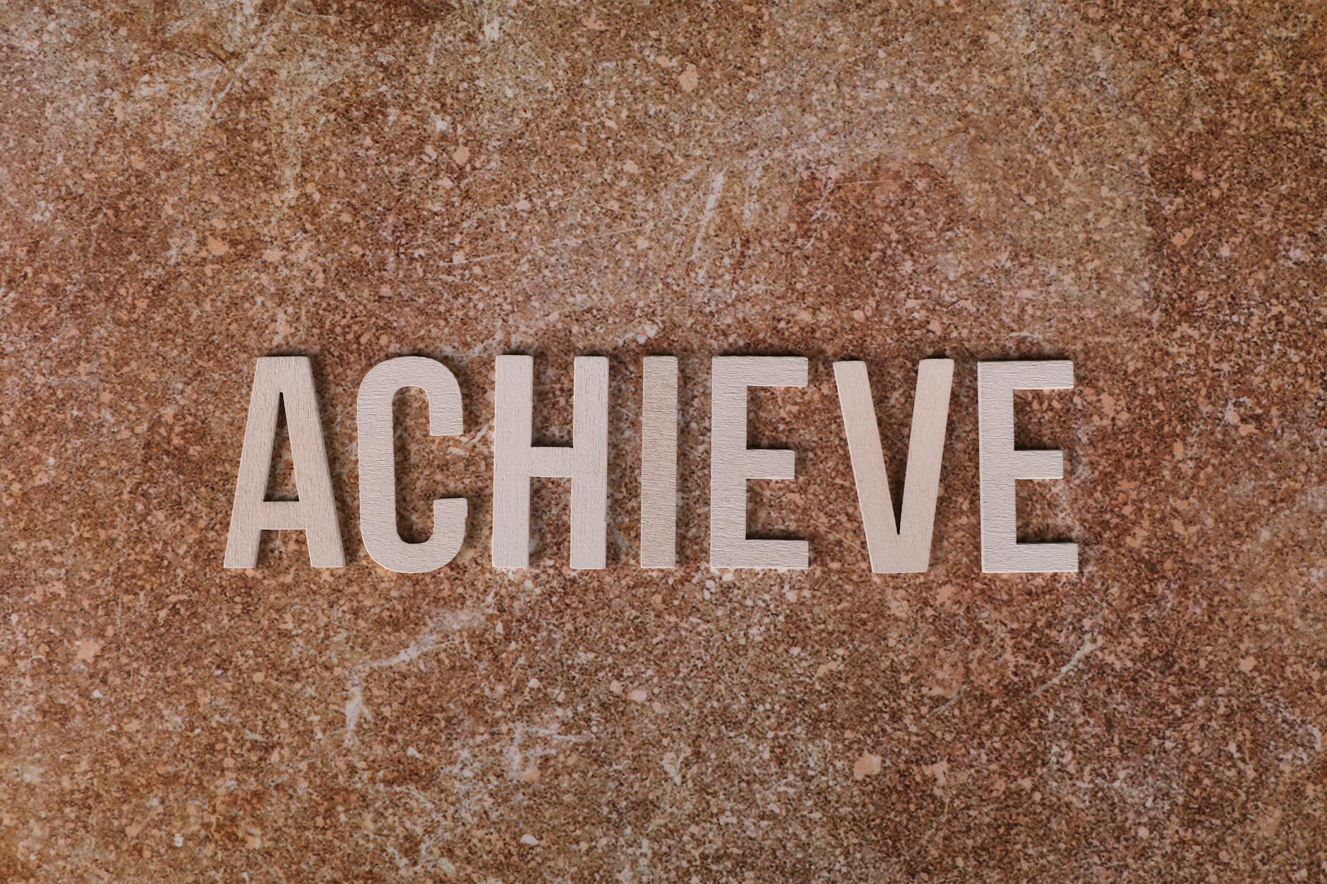 Wooden letters spelling 'ACHIEVE' on a textured brown surface, conveying motivation and success. - achievable therapy goals