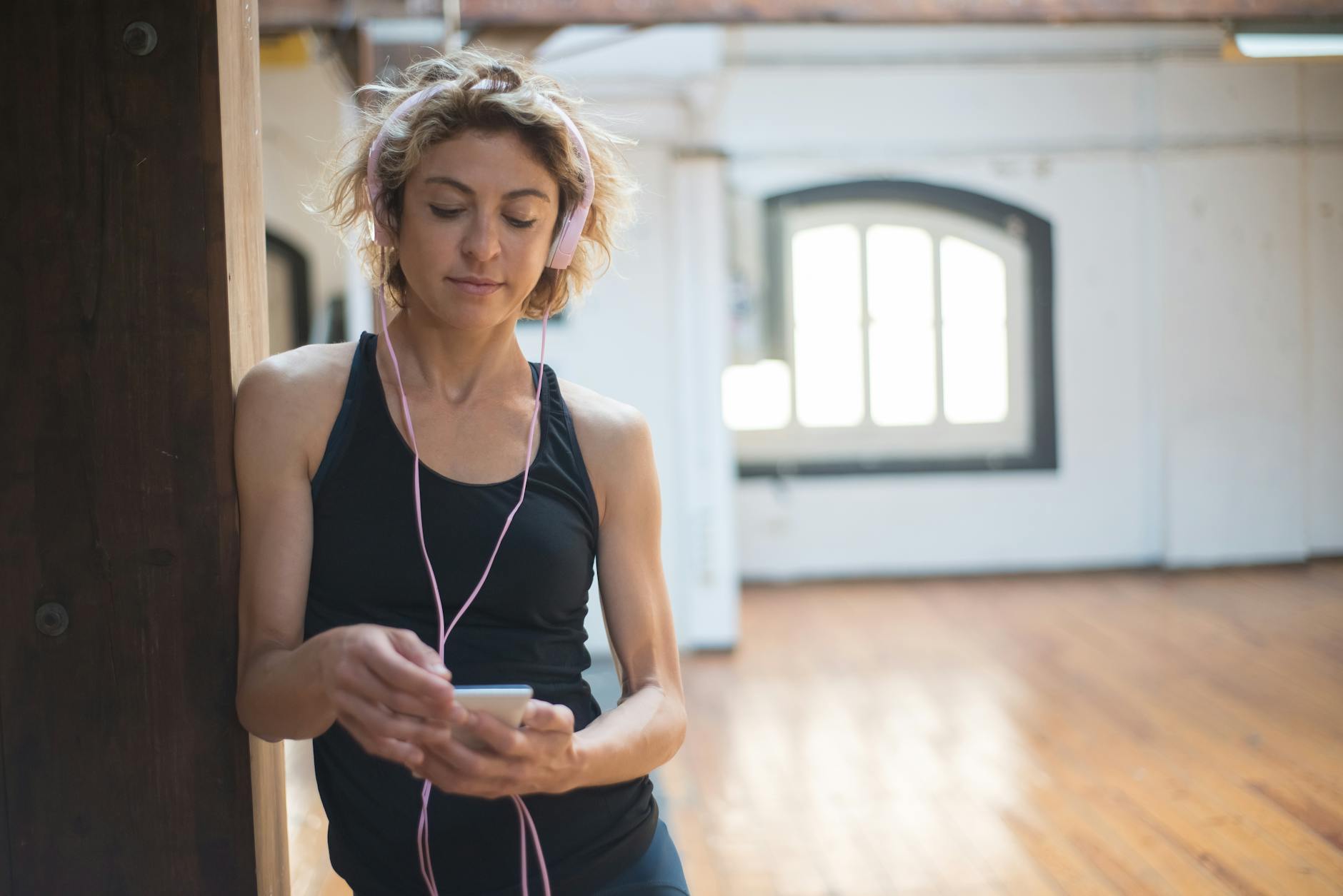 Blonde woman in a dance studio listening to music on her phone, conveying a serene and focused ambiance. - active listening examples
