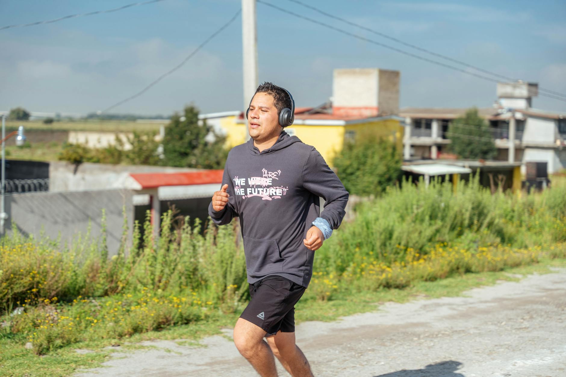 A man runs outdoors listening to music, showcasing rural surroundings and focus on fitness. - active listening importance
