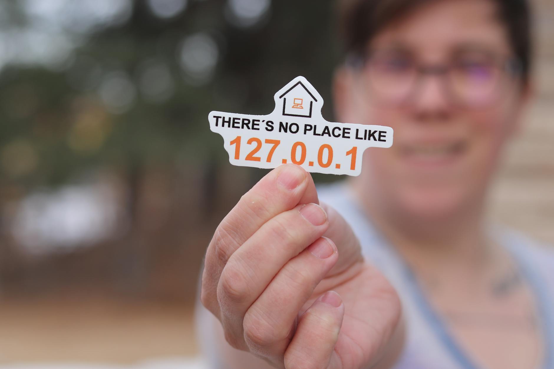 Close-up of a hand holding a tech-themed sticker with a home symbol and numbers. - address unspoken issues