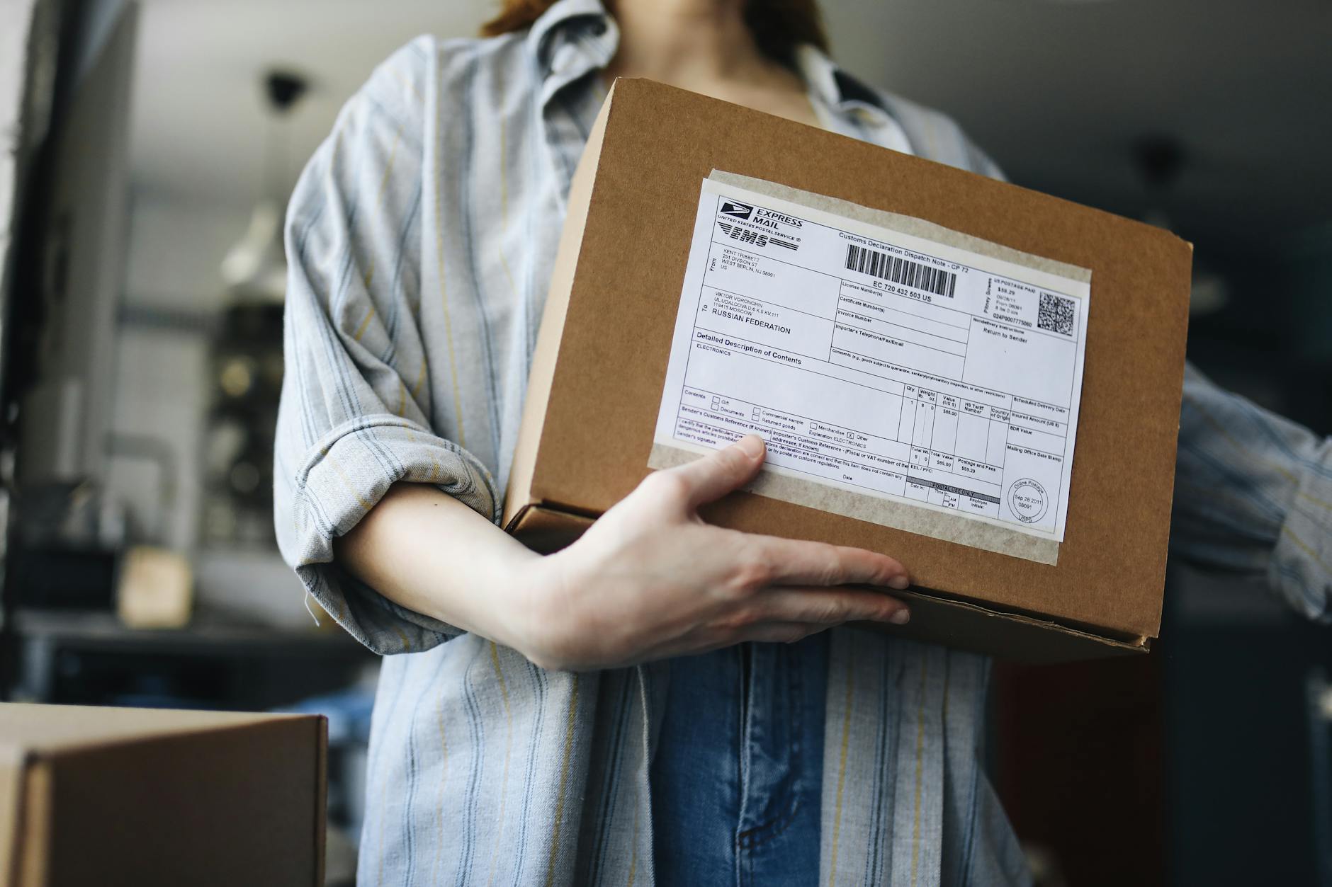 Close-up of a woman holding a parcel indoors, showcasing postal and delivery themes. - address unspoken issues