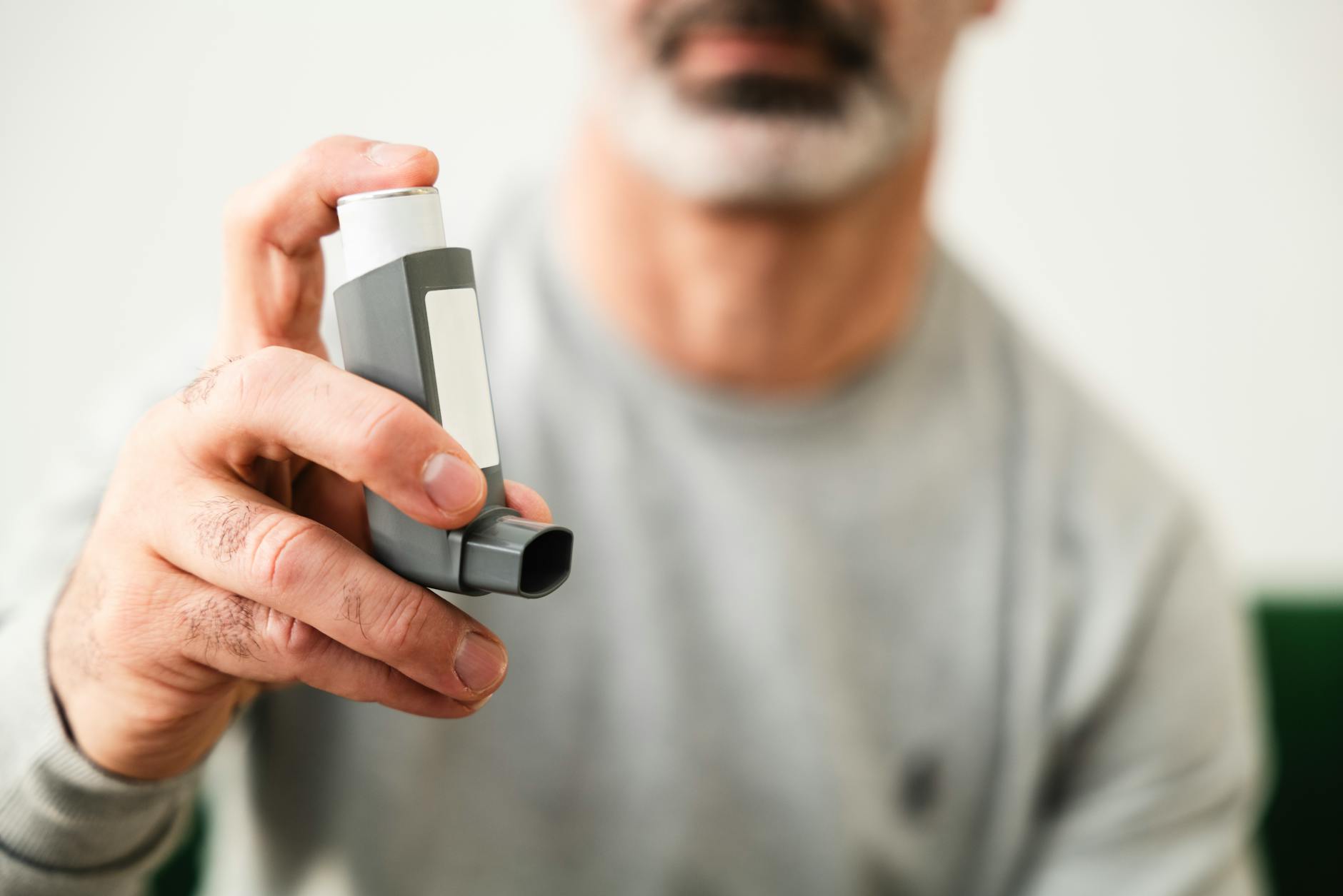 Man using an inhaler for respiratory health indoors. - allergies mood focus
