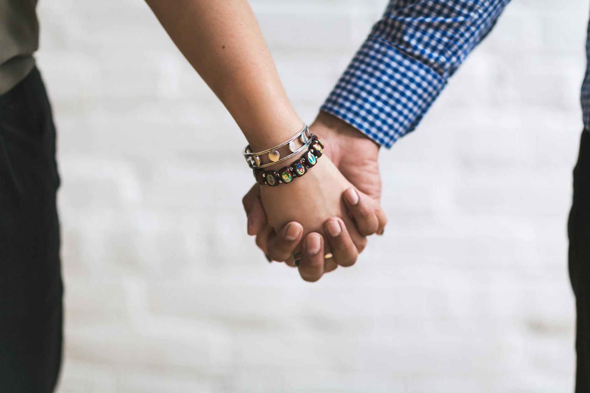 A close-up image of a couple holding hands outdoors symbolizing togetherness and unity. - attachment style quiz