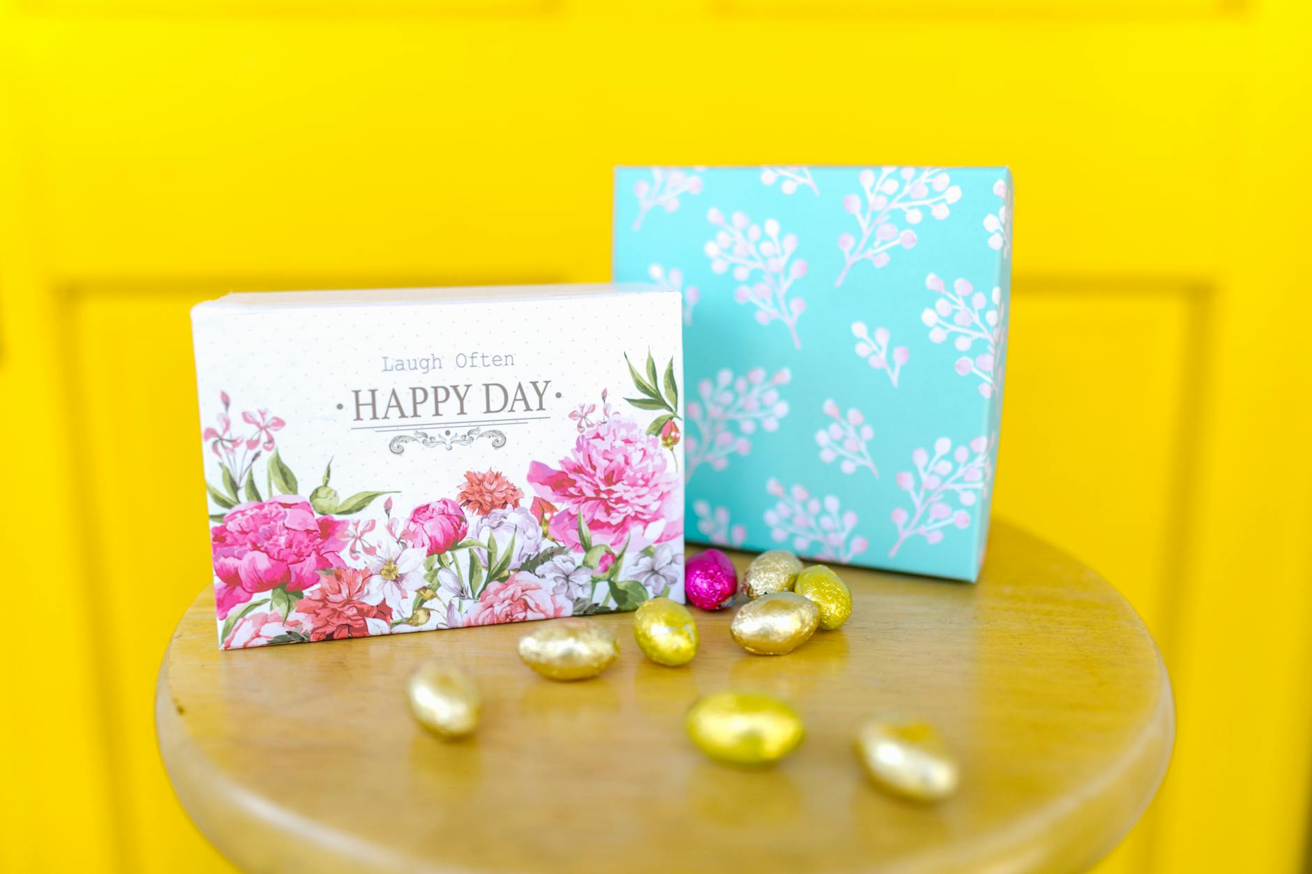A vibrant Easter-themed gift box with floral designs and colorful decorative eggs on a wooden table. - blended family spring holidays