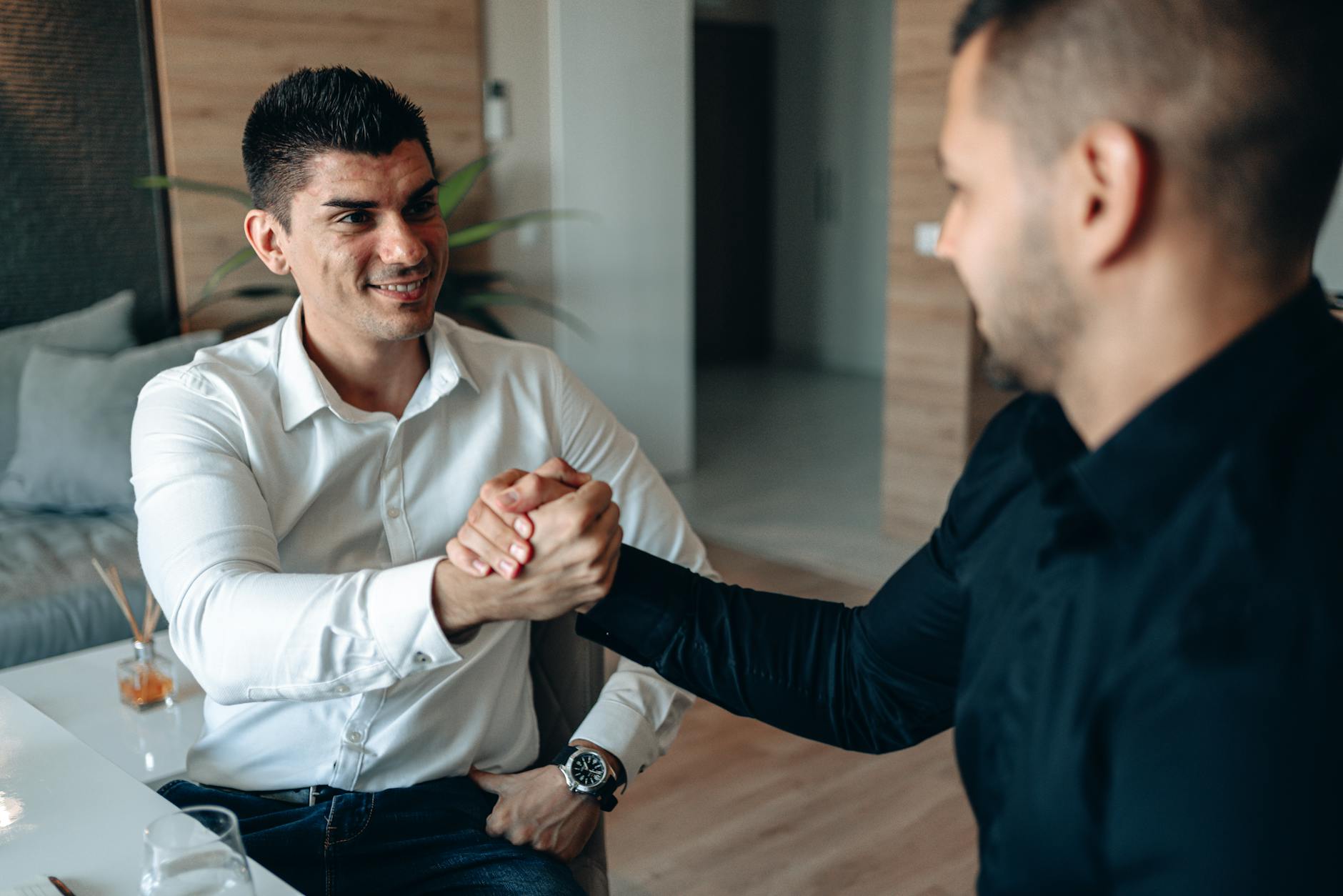 Two businessmen shaking hands in a modern office setting, sealing a successful deal. - build trust relationships