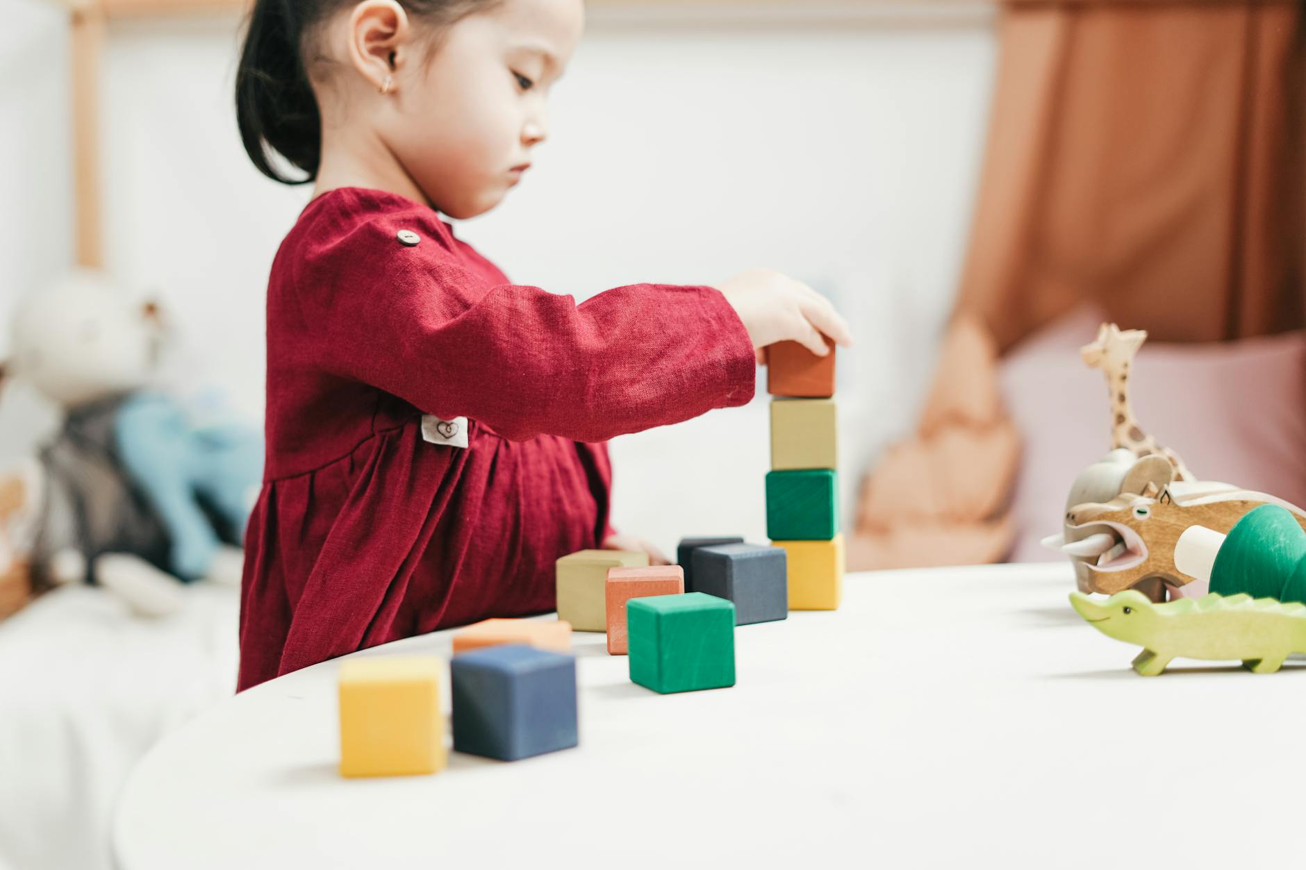 A young girl engaging with colorful wooden blocks, fostering creativity and learning in a playroom. - childhood meltdowns