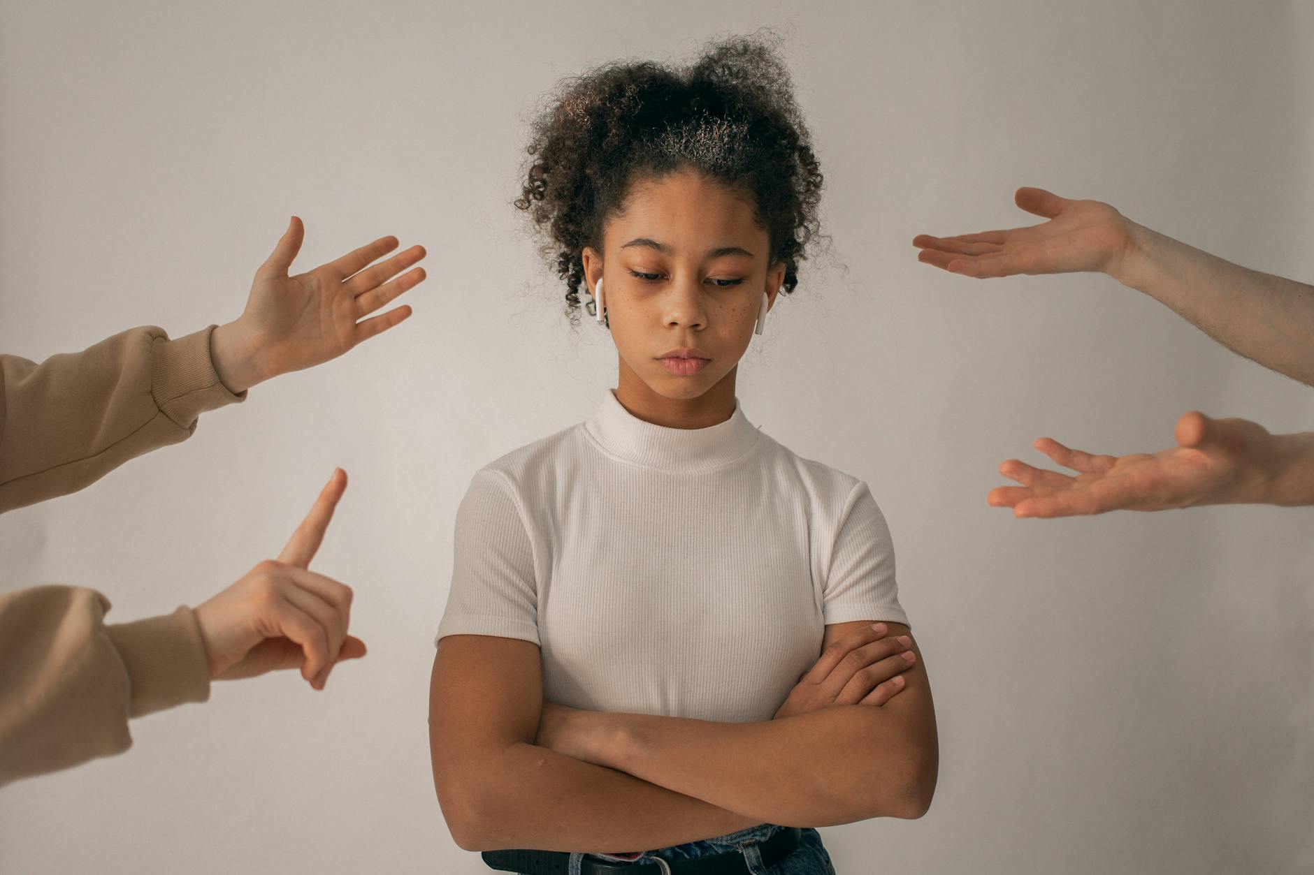 A teenage girl looks upset while expressive hands point and gesture around her. - what is conflict