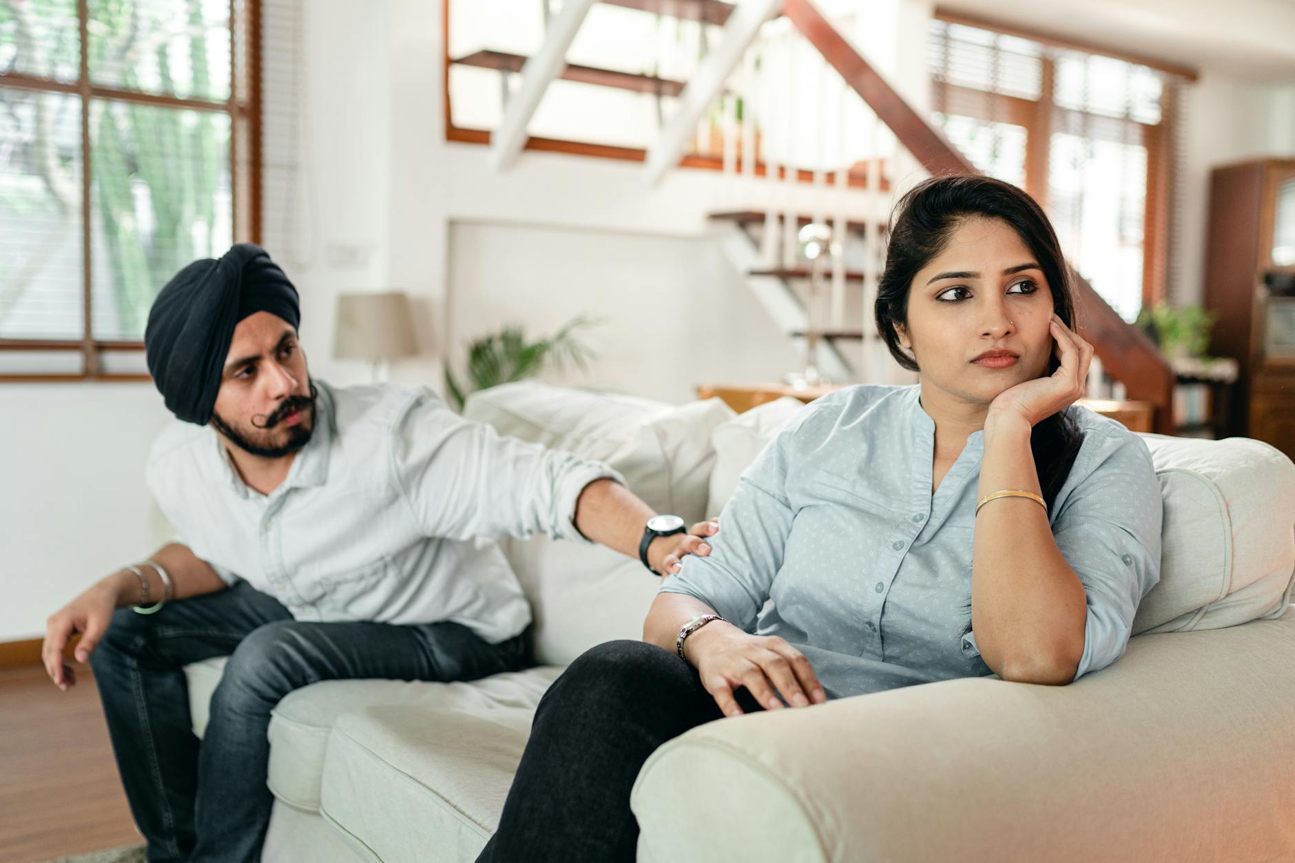 A couple sitting on a couch indoors, appearing upset and in conflict. Emotional tension. - couple communication skills