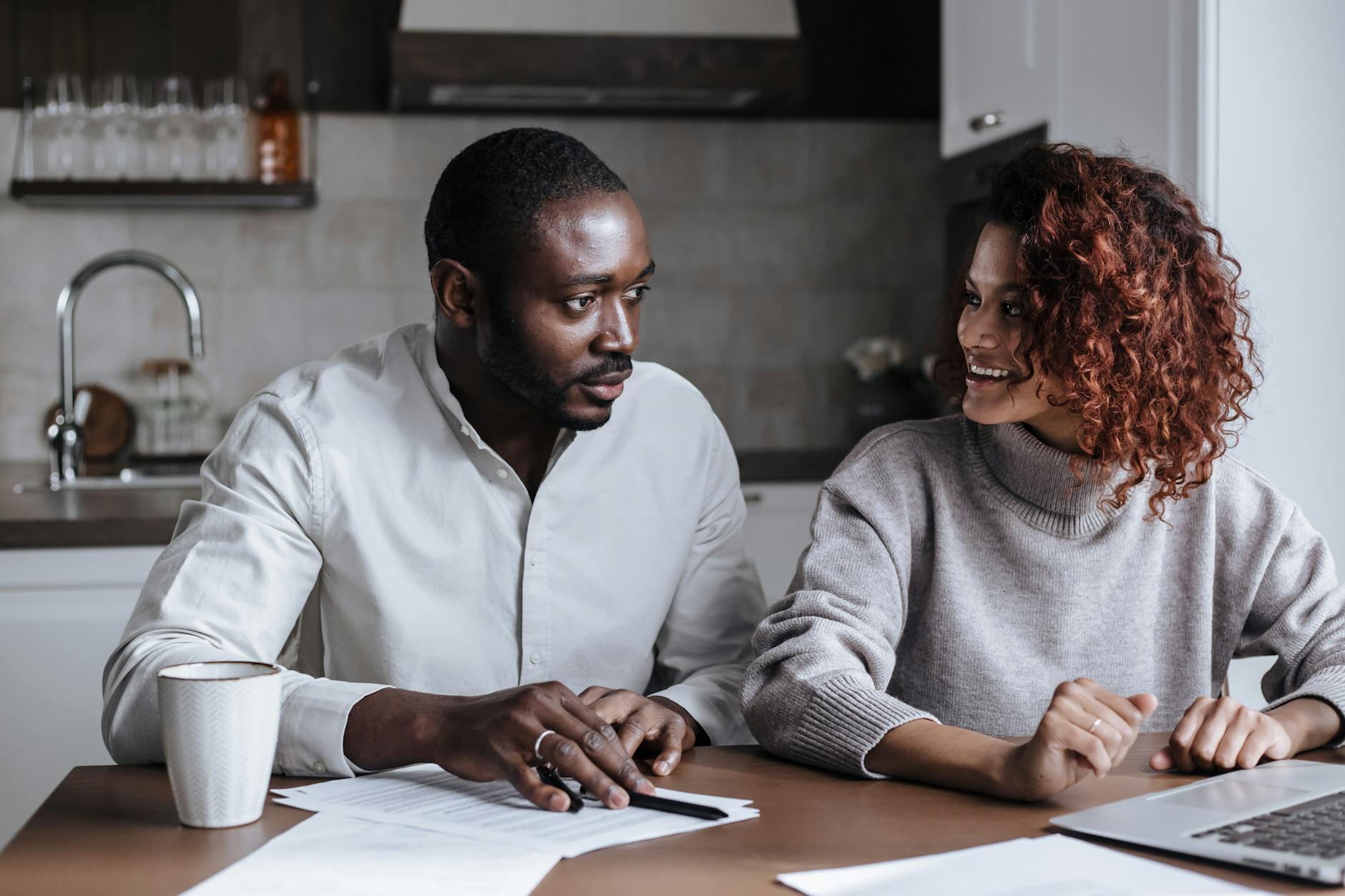 Black couple collaborating on a project at their kitchen table, showcasing teamwork and home office lifestyle. - couple travel planning communication