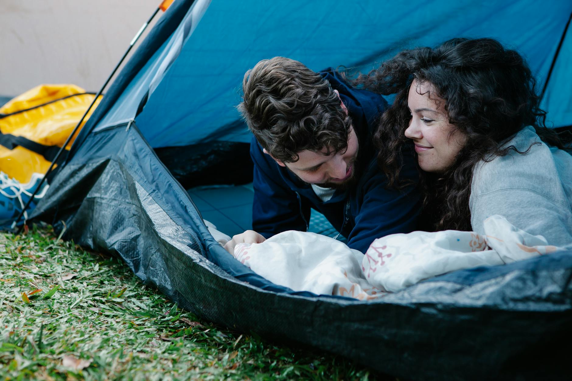 A cheerful couple enjoys a romantic moment in their outdoor camping tent. - couples spring reconnection