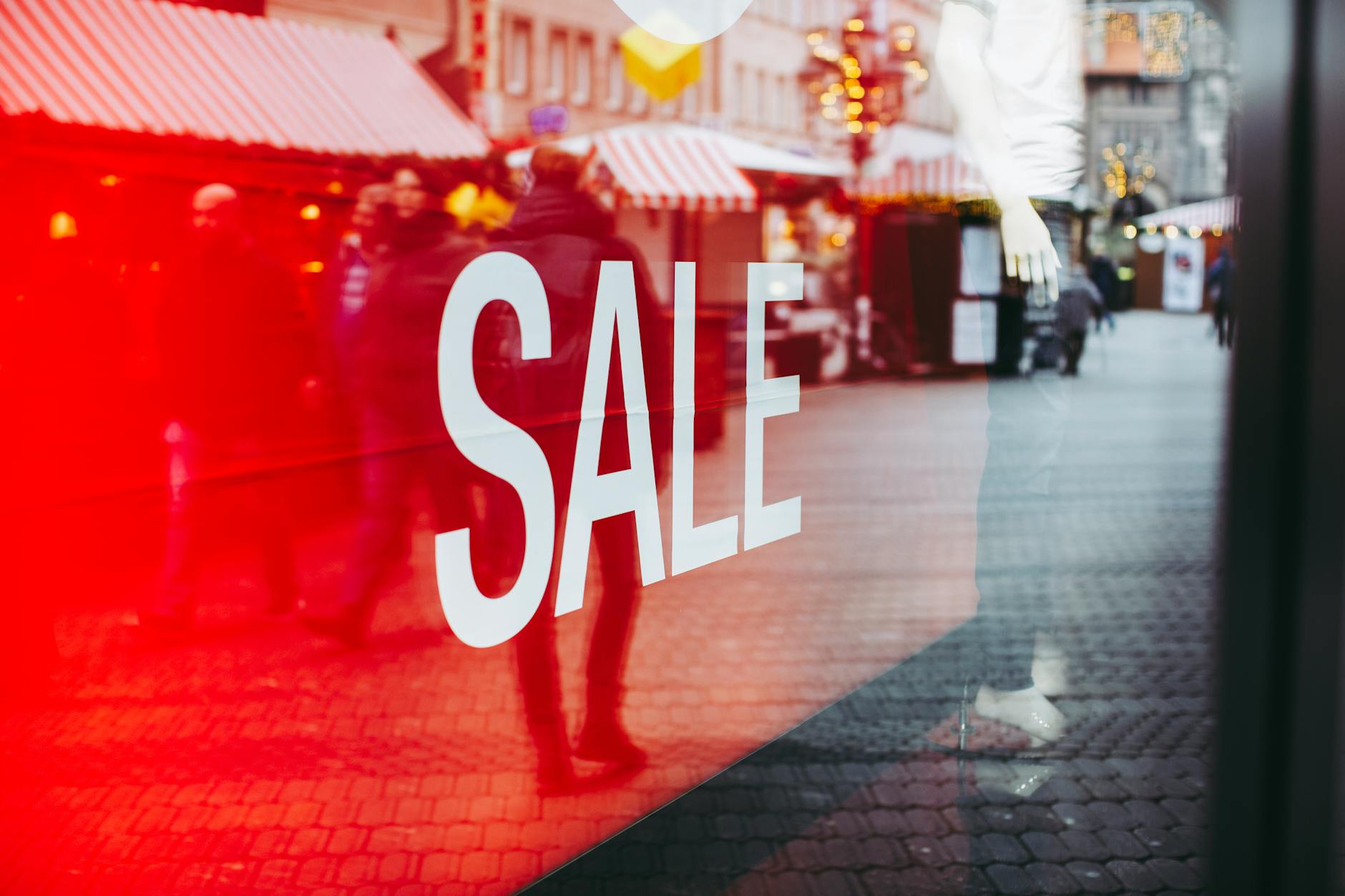 Red sale sign on storefront window reflecting a busy urban street scene, capturing city life. - couples therapy signs