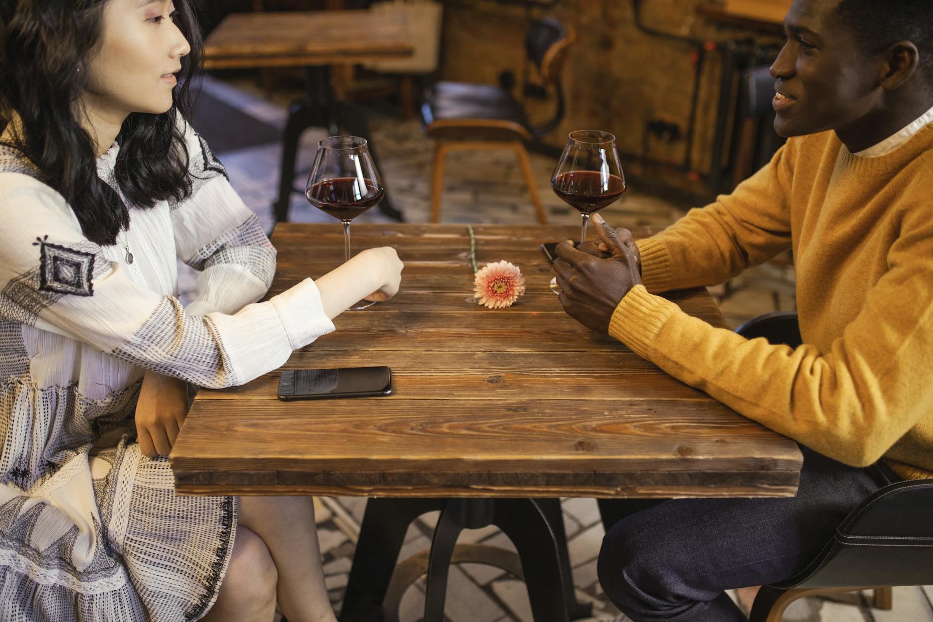 Interracial couple enjoying a romantic date with wine in a cozy café setting. - dating tips introverts