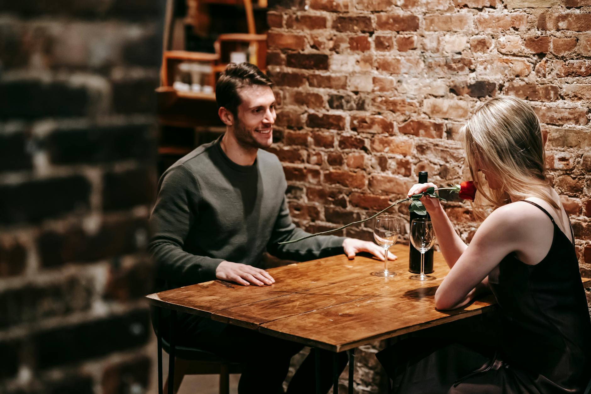 A couple enjoying a romantic dinner with rose and wine in a cozy restaurant setting. - dating tips introverts